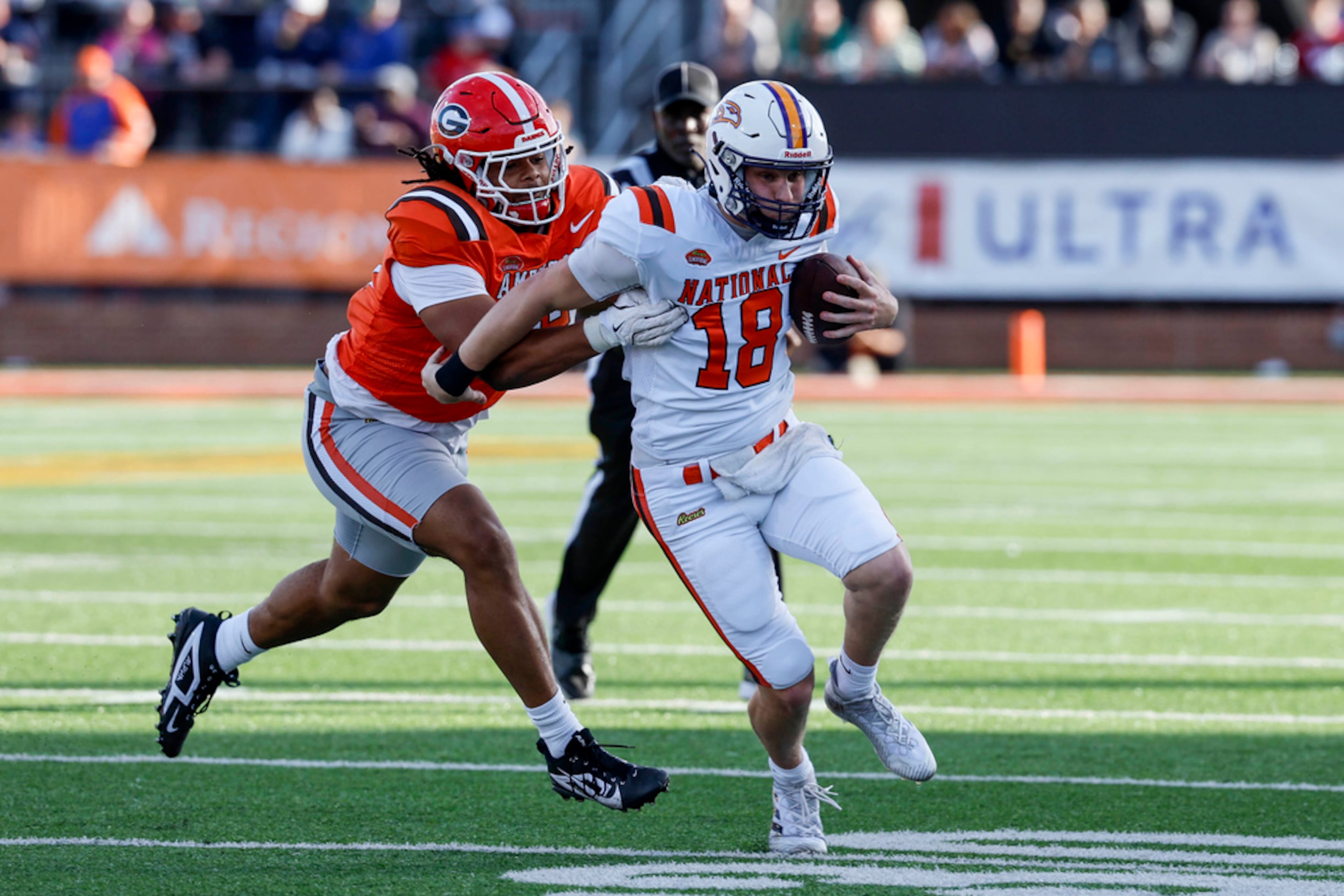 National team quarterback Taylor Elgersma (18), of Laurier, scrambles as American team defensive lineman Tyrion Ingram-Dawkins, left, of Georgia, tackles him from behind during the second half of the Senior Bowl NCAA college football game, Saturday, Feb. 1, 2025, in Mobile, Ala. (AP Photo/Butch Dill)