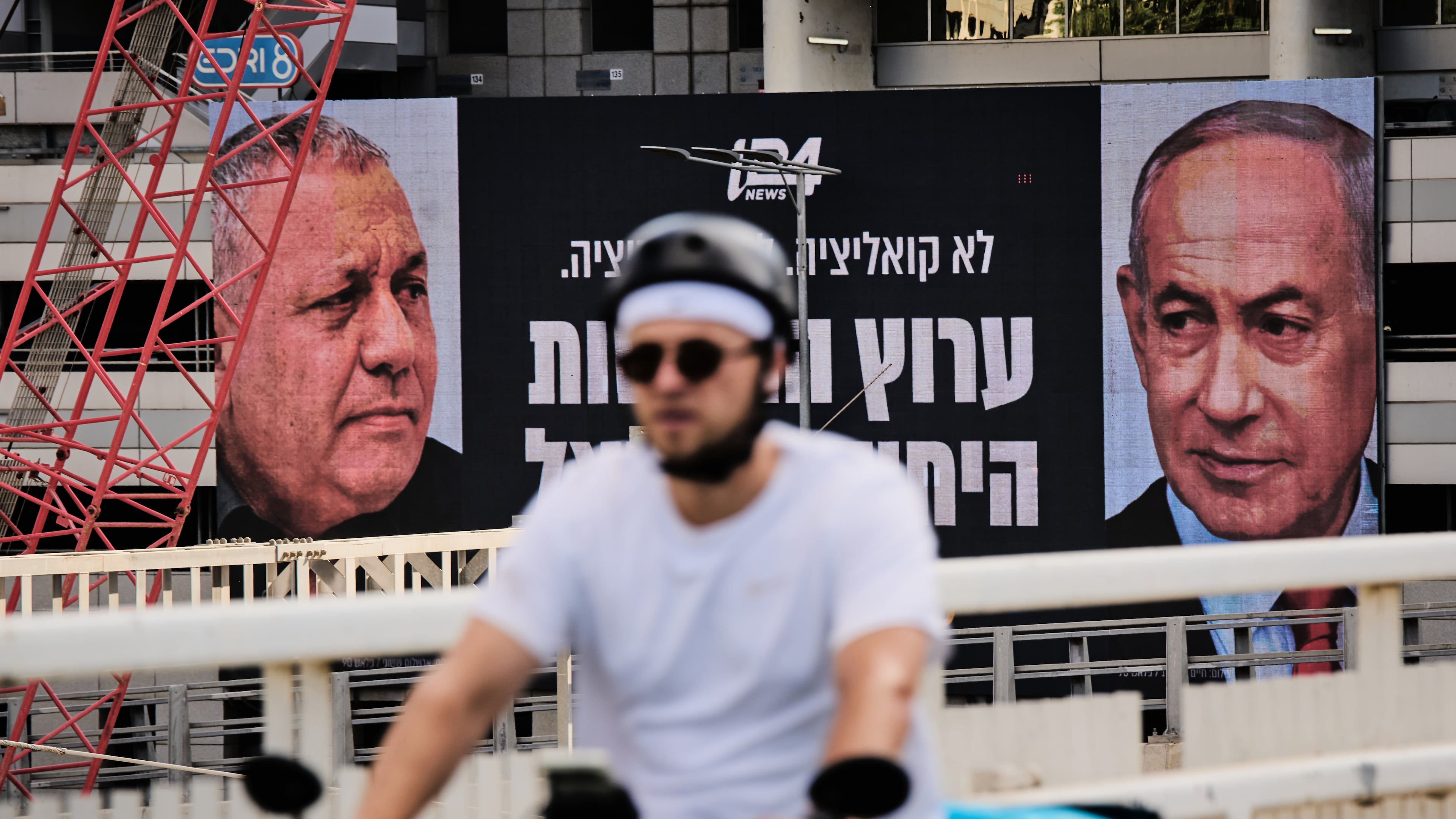 A man rides bicycle past a television channel advertisement featuring Israeli Prime Minister Benjamin Netanyahu, right, and his main rival, opposition candidate Gadi Eisenkot, ahead of Israel's general election, in Ramat Gan, Israel, Wednesday, Sept. 23, 2026. (AP Photo/Oded Balilty)