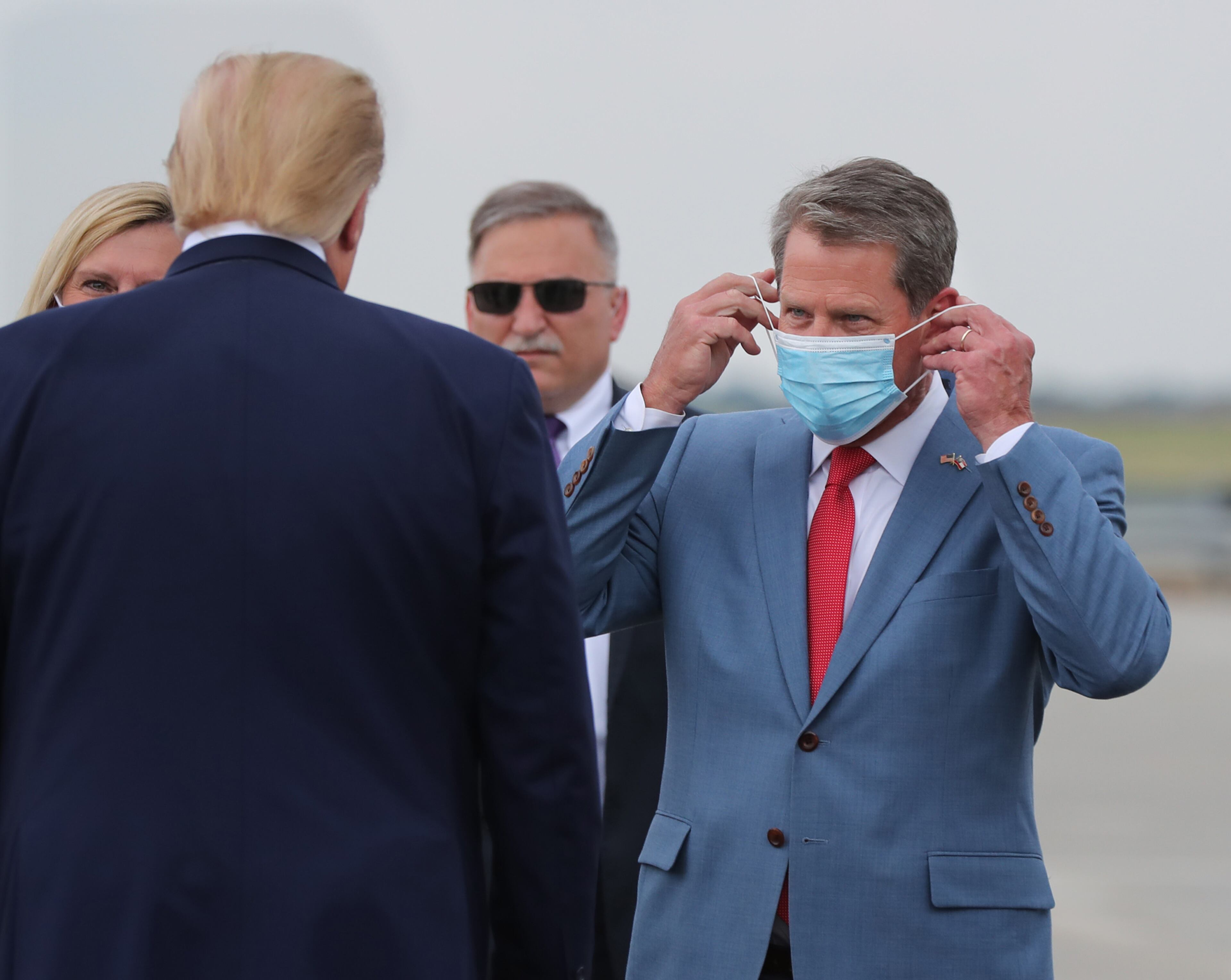 Kemp adjusts his face mask as he greets then-President Donald Trump at Hartsfield-Jackson International Airport in July 2020. Earlier that month, Kemp and Toomey toured the state to promote wearing masks, albeit voluntarily. (Curtis Compton / ccompton@ajc.com)