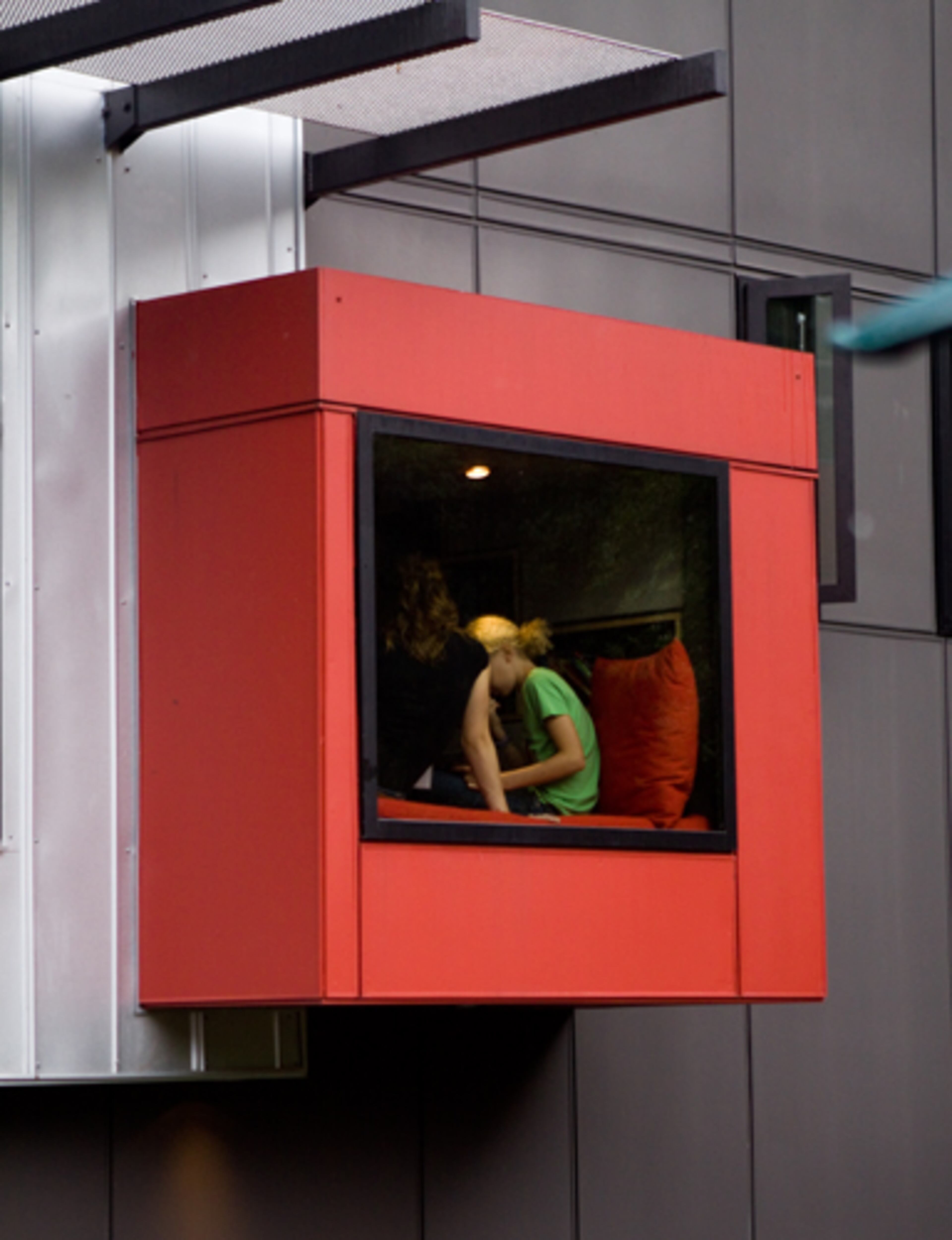 The ordered elegance of the library’s interior shelves is echoed to dramatic effect with the protruding iconic red boxes that stop traffic and define the space’s exterior.