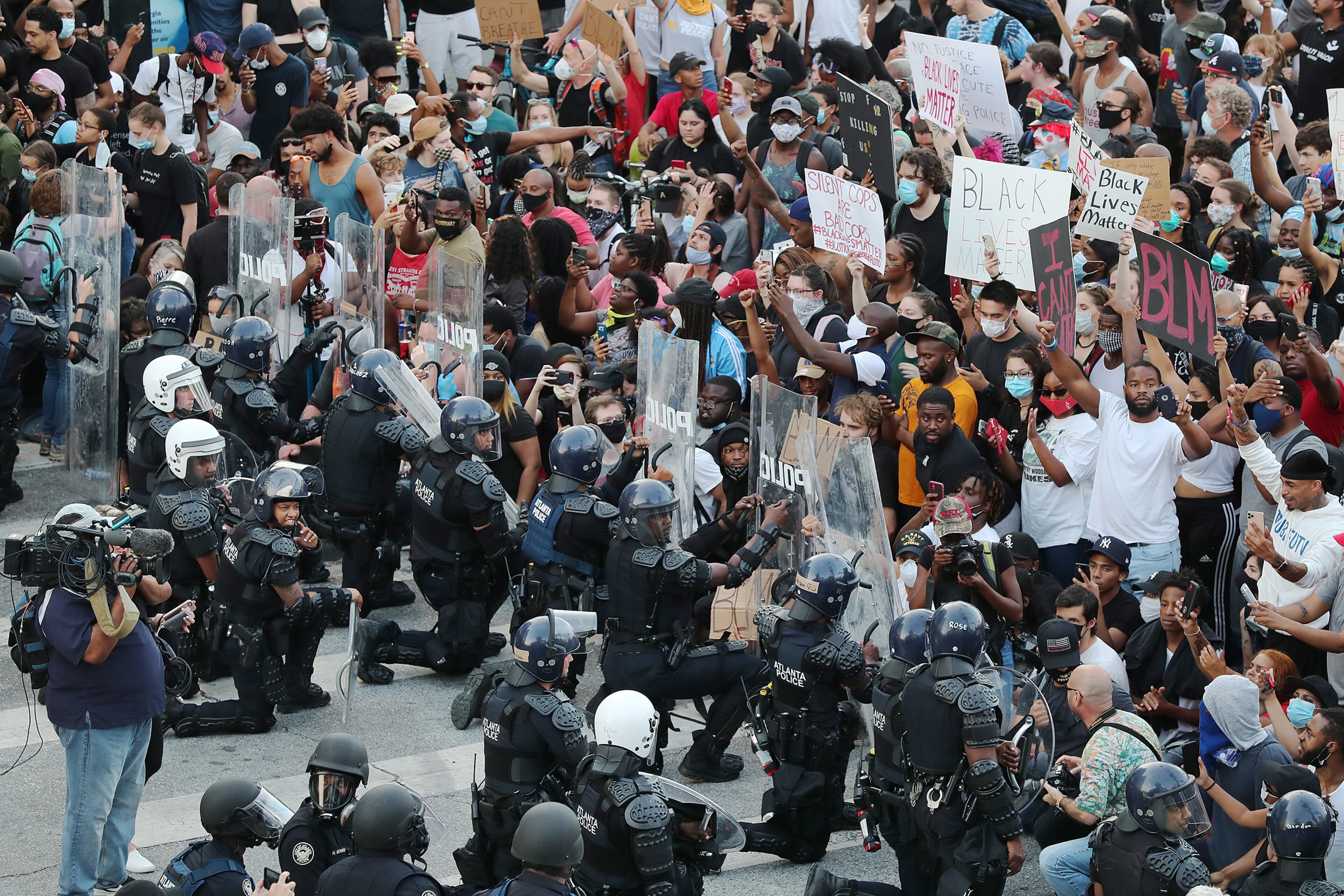 In a show of peace and solidarity law enforcement officials with riot shields take a knee before protesters during a fourth day of protests on Monday, June 1, 2020, in Atlanta. Curtis Compton ccompton@ajc.com