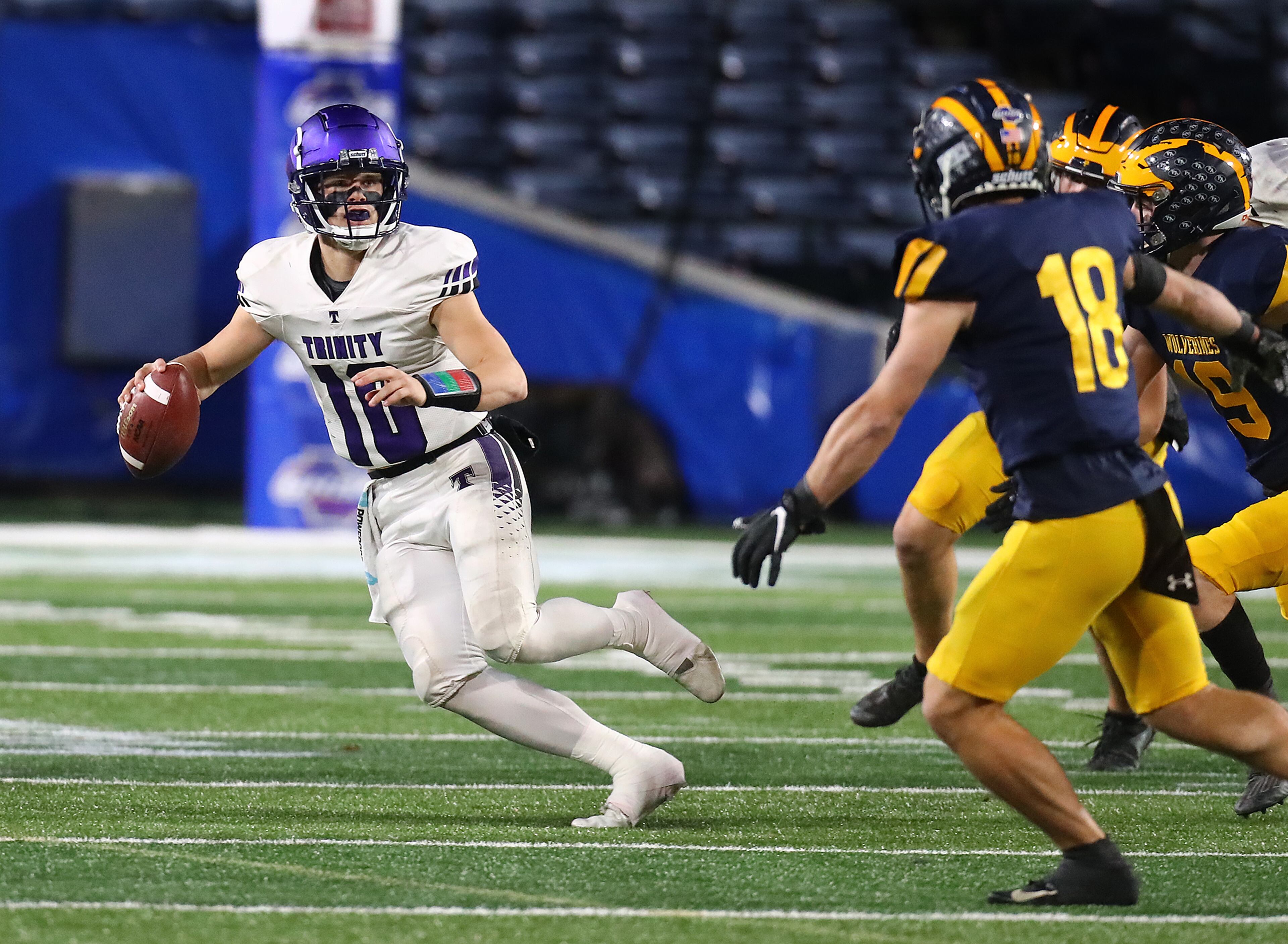 Trinity Christian quarterback David Dallas looks to pass as he rolls out of the pocket under pressure from Prince Avenue Christian defenders in their GHSA Class A Private Championship game on Thursday, Dec 9, 2021, in Atlanta. “Curtis Compton / Curtis.Compton@ajc.com”`