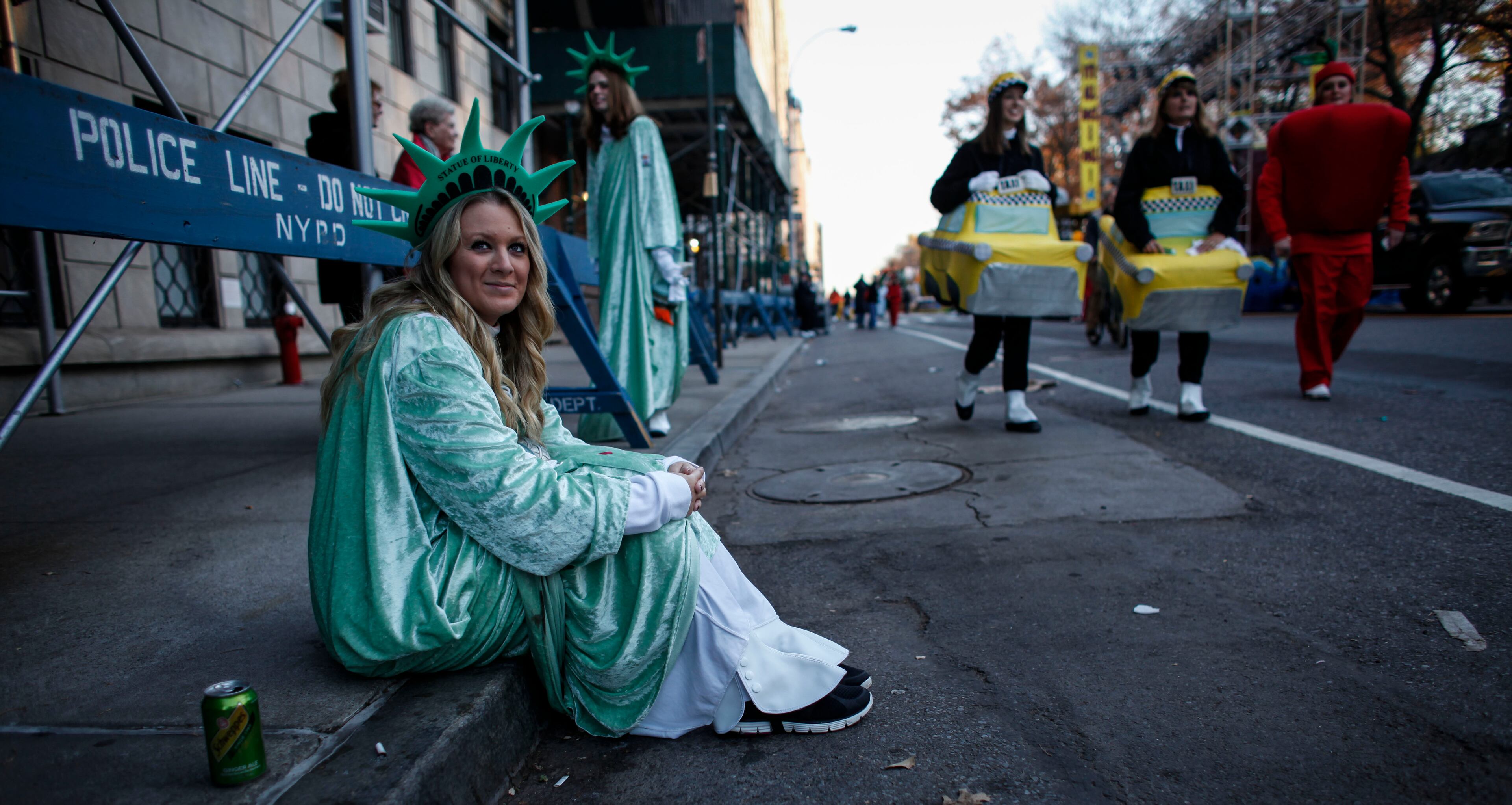 NEW YORK, NY - NOVEMBER 26: A woman dress up as Statue of liberty waits before the Annual Thanksgiving Parade on November 26, 2015 in New York City. A record number of police officers were patrolling the parade as security is on a high alert after the terror attacks in Paris and threats made to the city. (Photo by Kena Betancur/Getty Images)