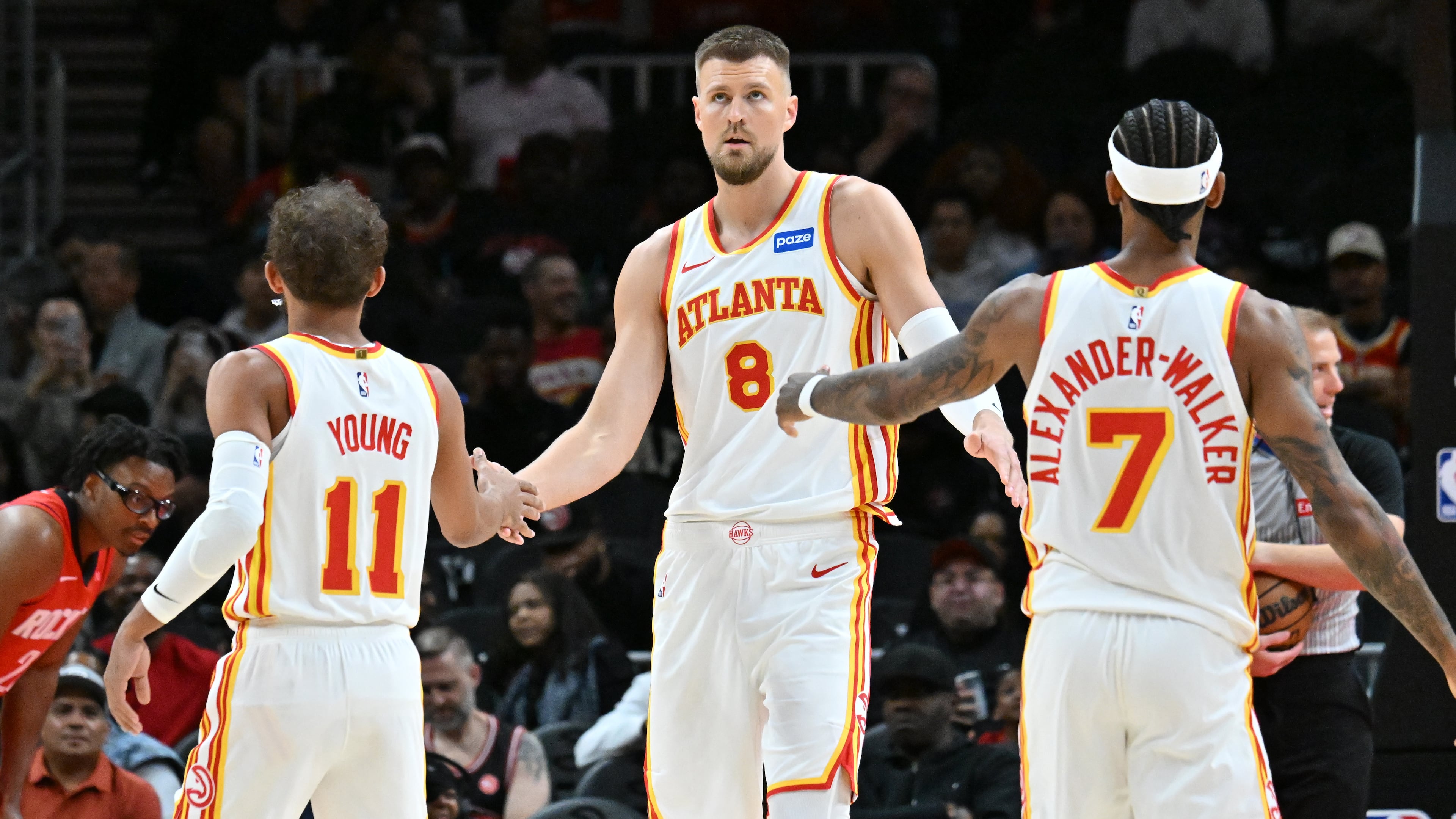 Atlanta Hawks forward/center Kristaps Porziņģis celebrates with Atlanta Hawks guard Trae Young and Atlanta Hawks guard Nickeil Alexander-Walker during a preseason game at State Farm Arena, Thursday, Oct. 16, 2025, in Atlanta. (Hyosub Shin/AJC)