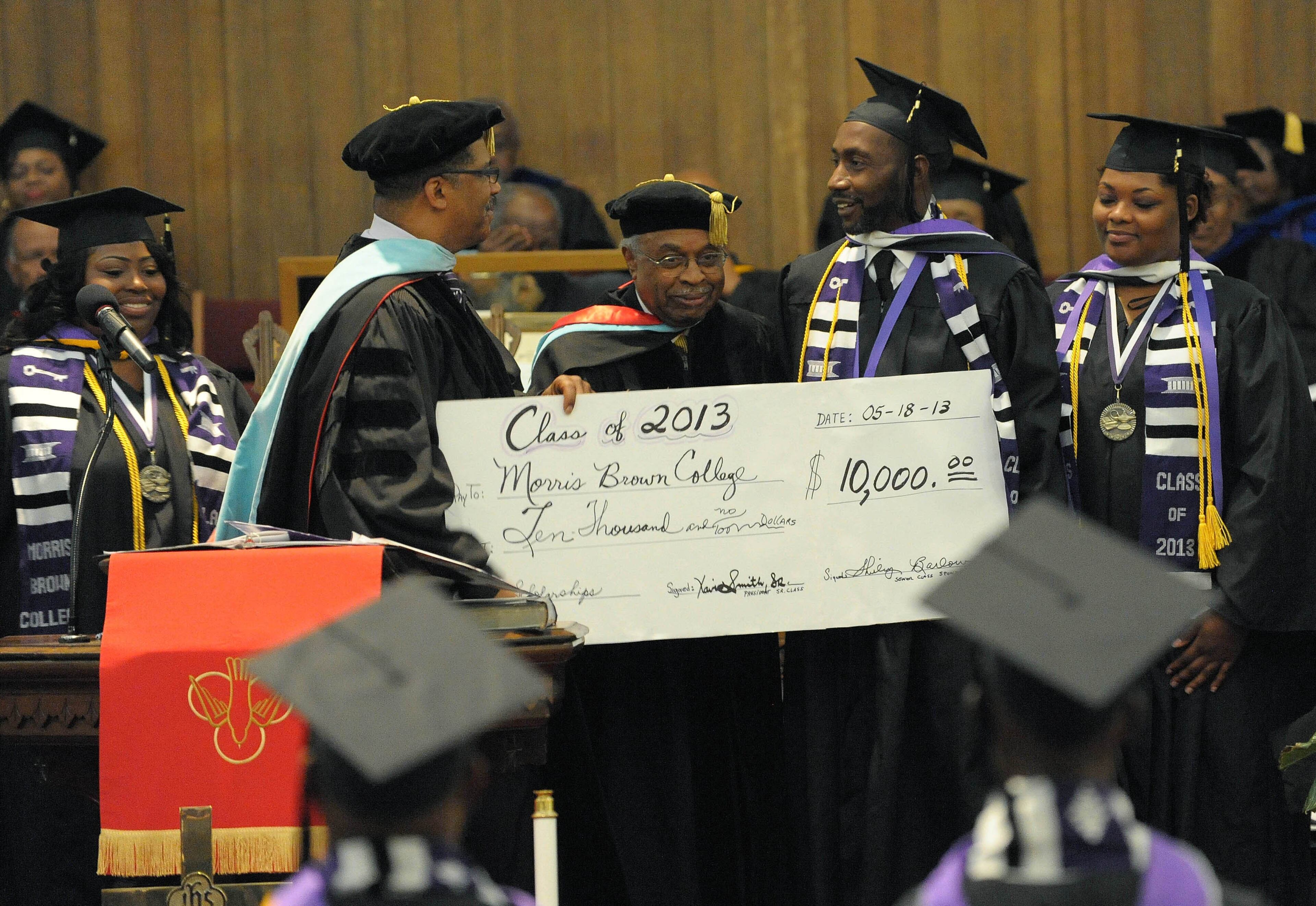 Morris Brown College graduates Xavier Smith, Cassandra Brown and Amber Pickens (left to right) present school president Stanley Pritchett and board of trustee member William "Sonny" Walker with a pledge of $10,000 from the 2013 graduating class at Saturday's commencement.