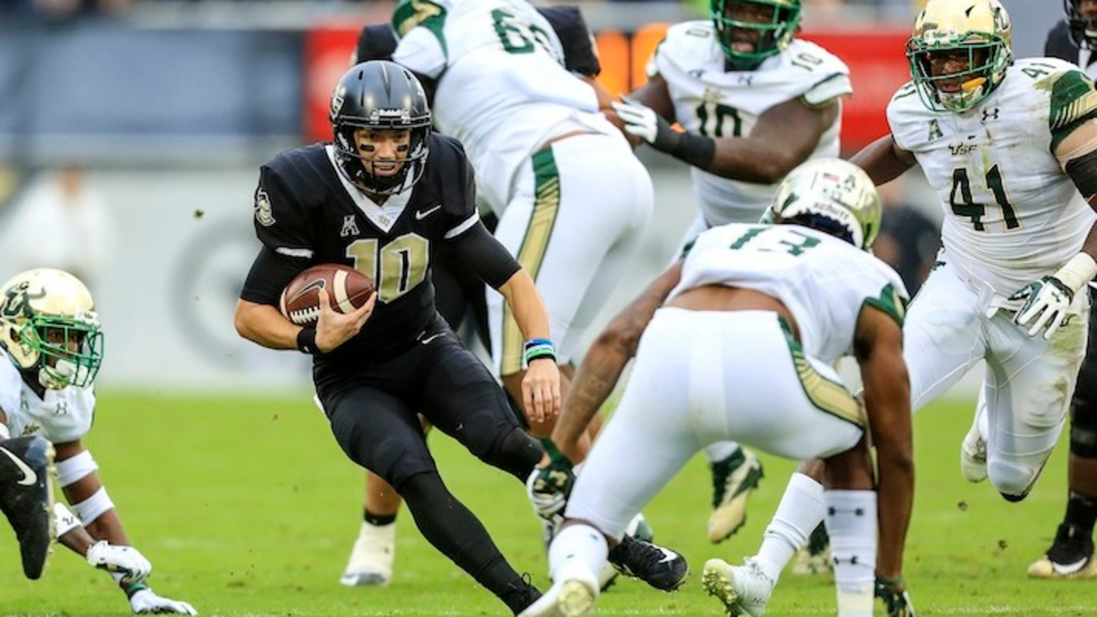 UCF quarterback Mckenzie Milton (10) runs the ball, looking to evade South Florida safety Tajee Fullwood (13) at Spectrum Stadium in Orlando, Fla., on Friday, Nov. 24, 2017. (Jacob Langston/Orlando Sentinel/TNS)