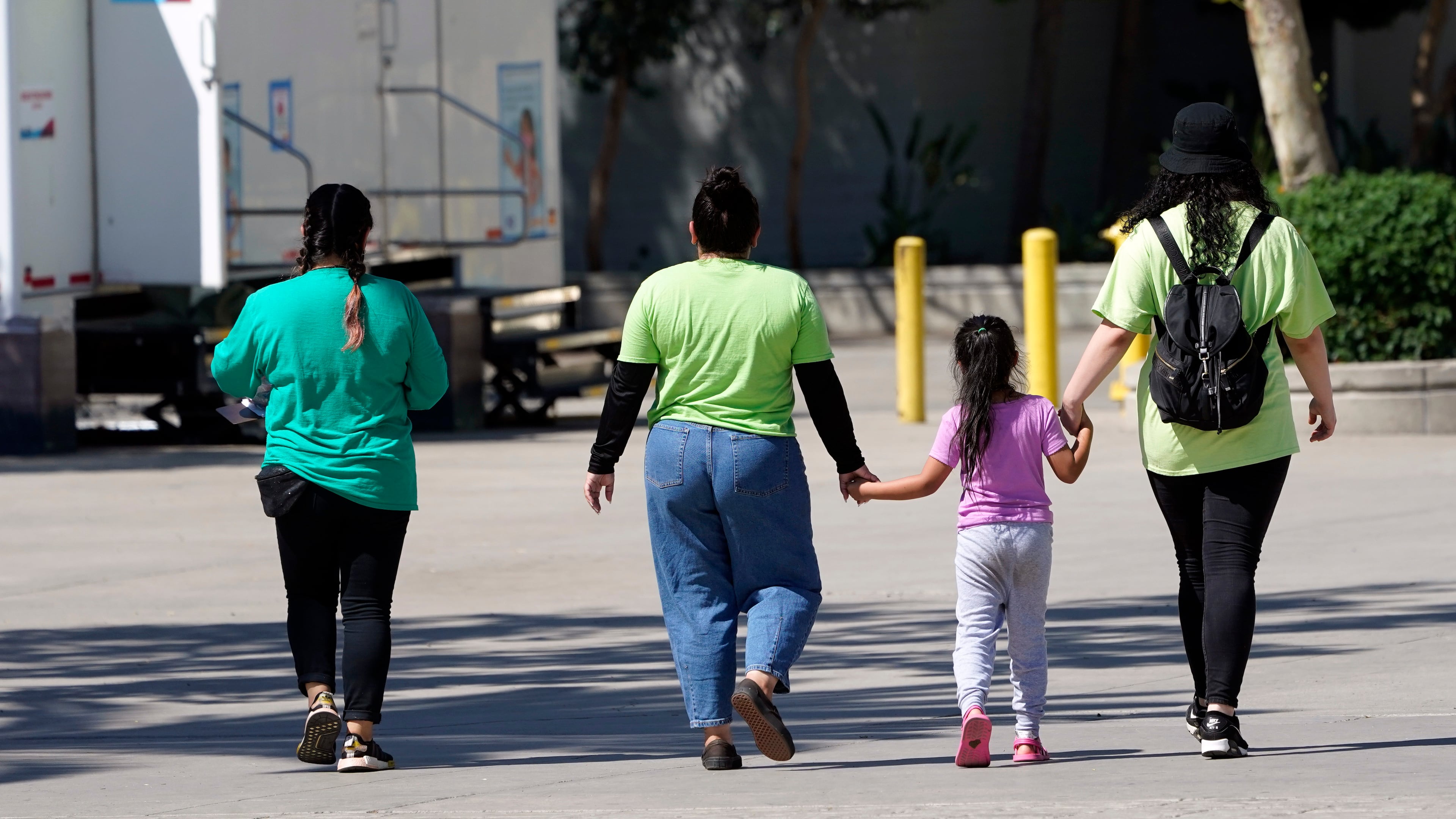 FILE - A child holds hands with workers at an emergency shelter for migrant children, July 2, 2021, in Pomona, Calif. (AP Photo/Marcio Jose Sanchez, Pool, File)