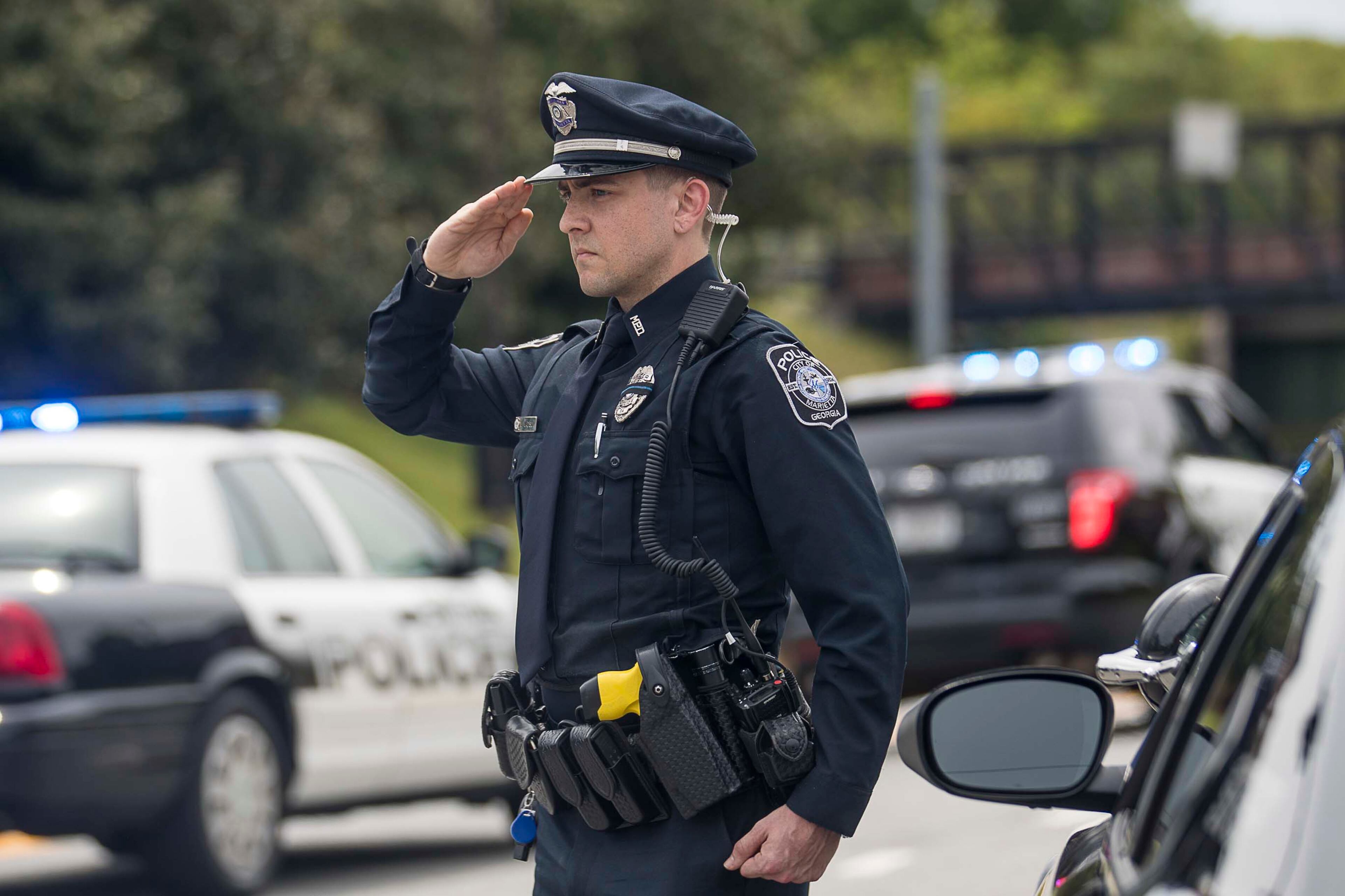 04/22/2020 - Marietta, Georgia - A Marietta Police Officer salutes as the motorcade that escorts the hearse carrying the body of fallen Smyrna Police Officer Christopher Ewing proceeds through downtown Marietta, Wednesday, April 22, 2020. Officer Ewing was killed in the line of duty when he was hit by a suspected drunk driver late Monday, April 20, according to police. Ewing was the first metro Atlanta officer killed this year in the line of duty. (ALYSSA POINTER / ALYSSA.POINTER@AJC.COM)