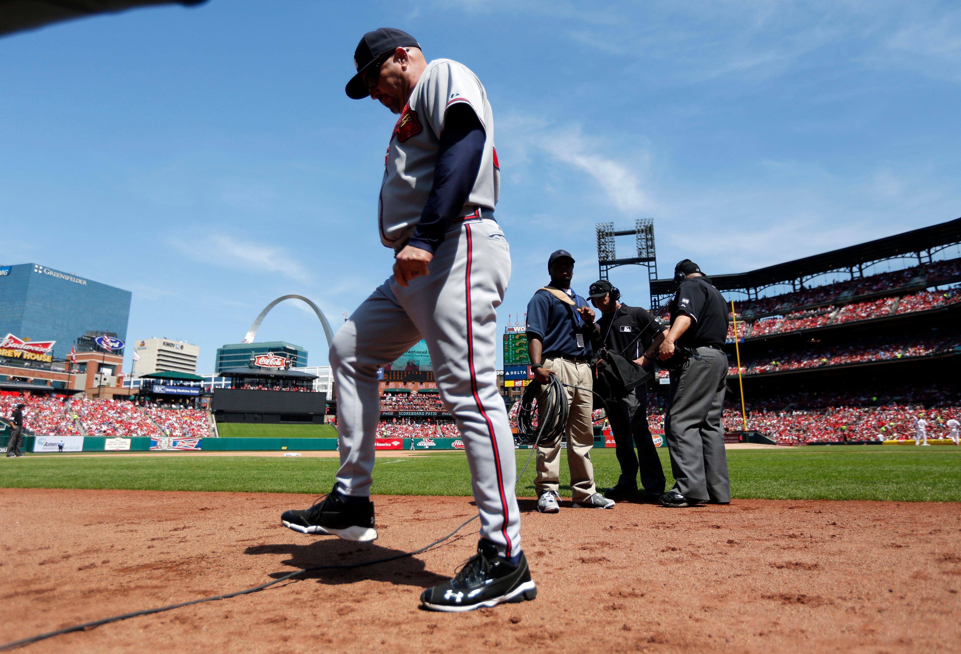 Atlanta Braves manager Fredi Gonzalez, left, steps over a cable as umpires Chris Guccione and Eric Cooper, right, review a call during the fifth inning of a baseball game Sunday, May 18, 2014, in St. Louis. (AP Photo/Jeff Roberson)