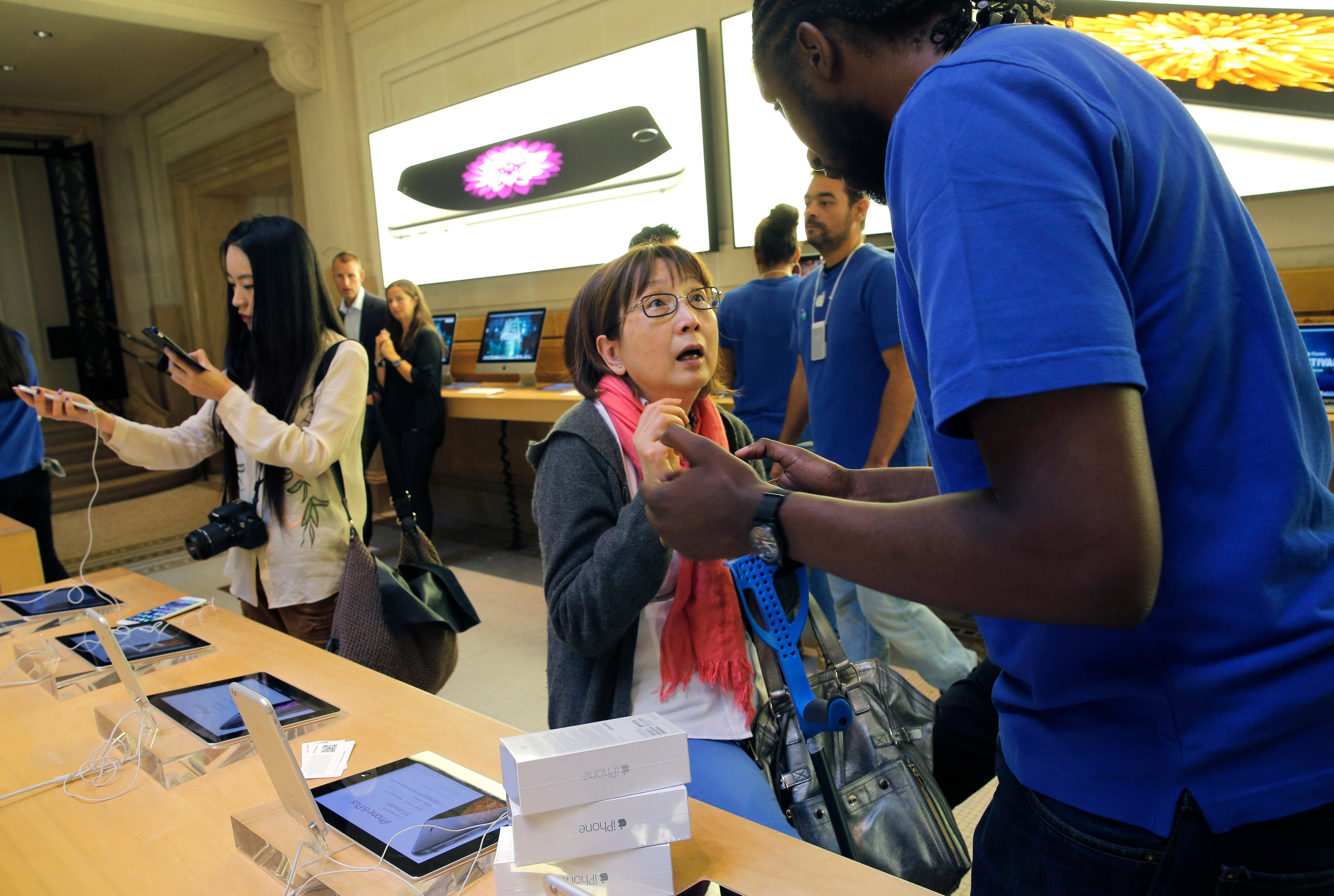 A salesman, right, gives some explanations to a customer in an Apple store as the new iPhone 6 goes on sale, Friday, Sept.19, 2014 in Paris. The iPhone 6 and 6 Plus have gone on sale in Australia, Japan and across Europe Friday. (AP Photo/Christophe Ena)