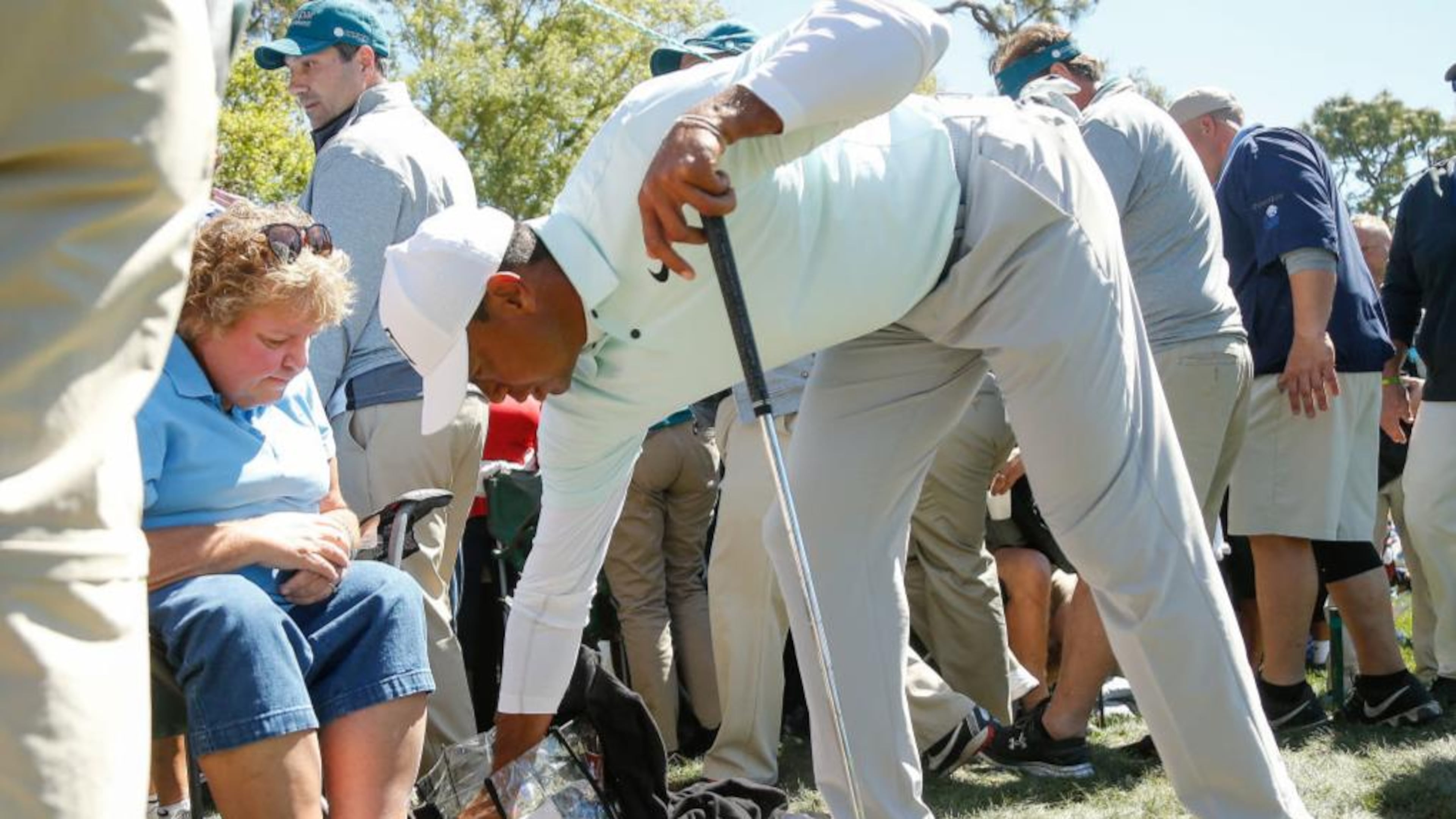 Tiger Woods removes his ball from the handbag of Marianna Cousins after hitting his second shot on the ninth hole during the second round of the Valspar Championship.