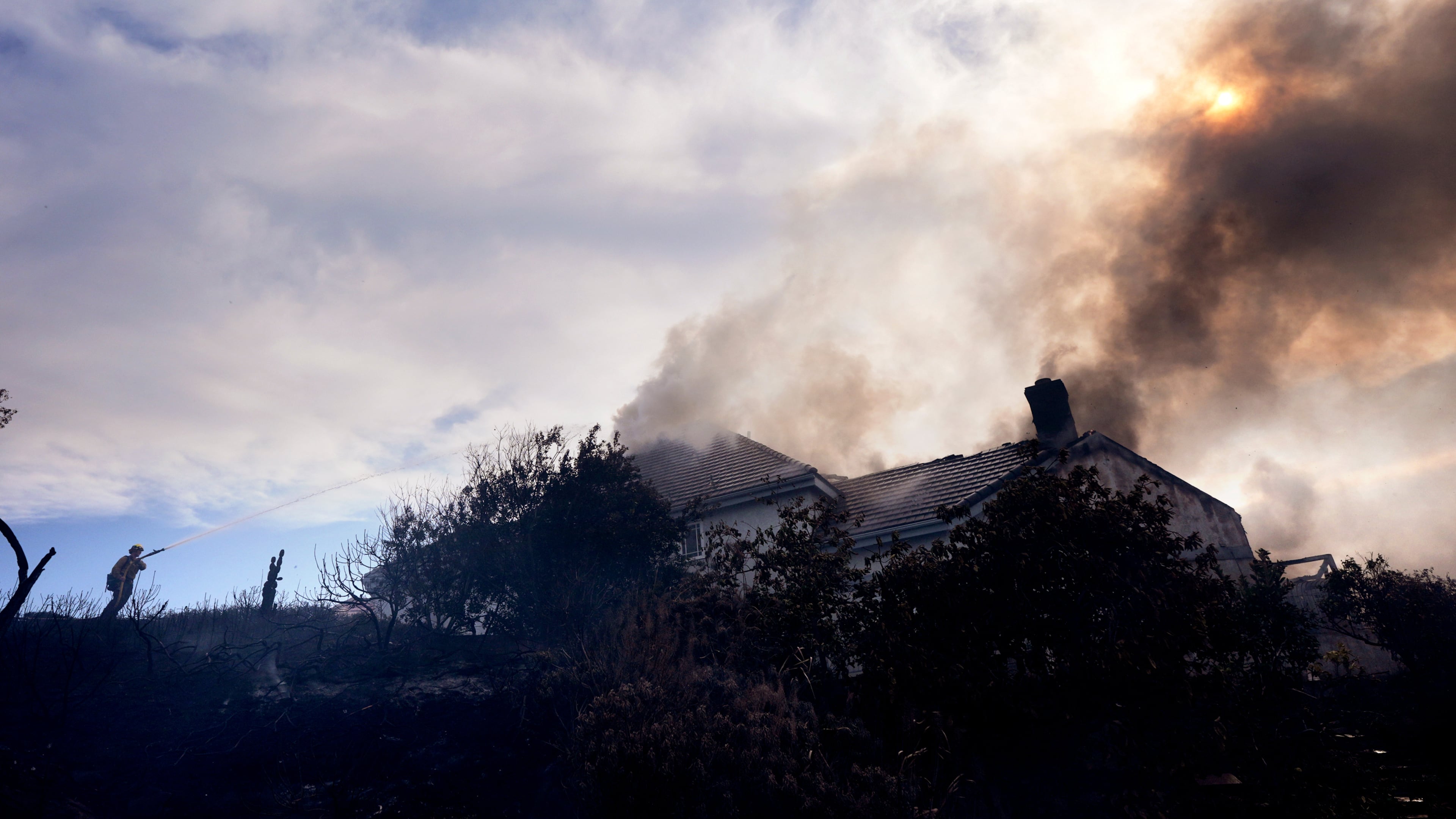 A firefighters works to put out a fire on a house engulfed in flames during the Norte Fire on Friday, Oct. 16, 2026, in San Juan Capistrano, Calif. (AP Photo/Jae C. Hong)