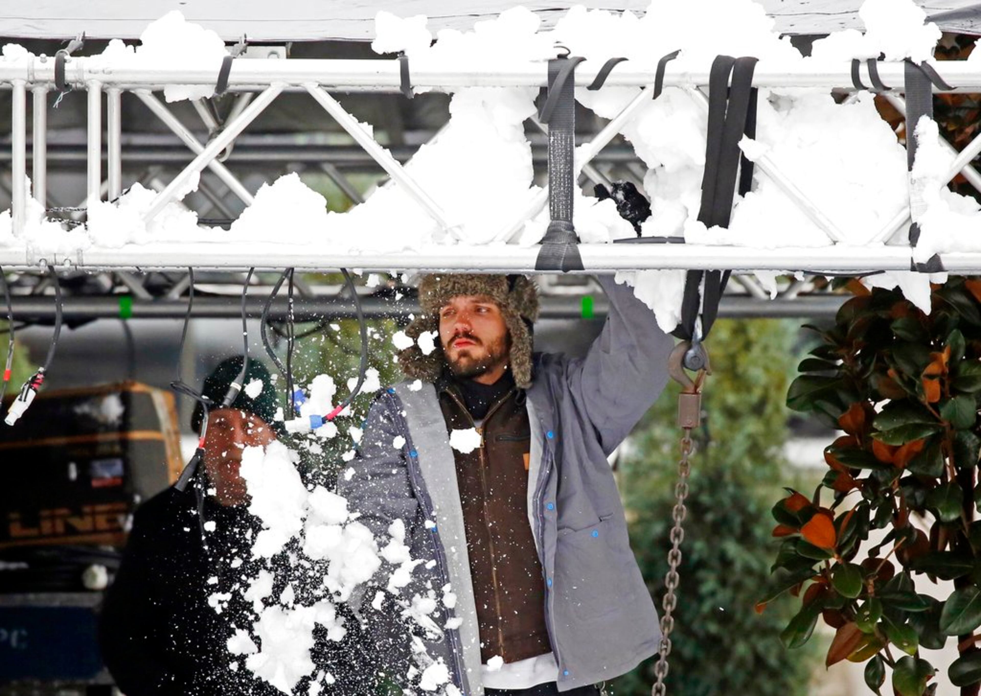 A crew member knocks off snow from the lighting brace that overhangs the main stage where the opening ceremonies for the state's two newest museums, Museum of Mississippi History and the Mississippi Civil Rights Museum, will take place, as preparations continue Friday, Dec. 8, 2017, in Jackson, Miss. Forecasters anticipate continued snowing across Deep South states. (AP Photo/Rogelio V. Solis)