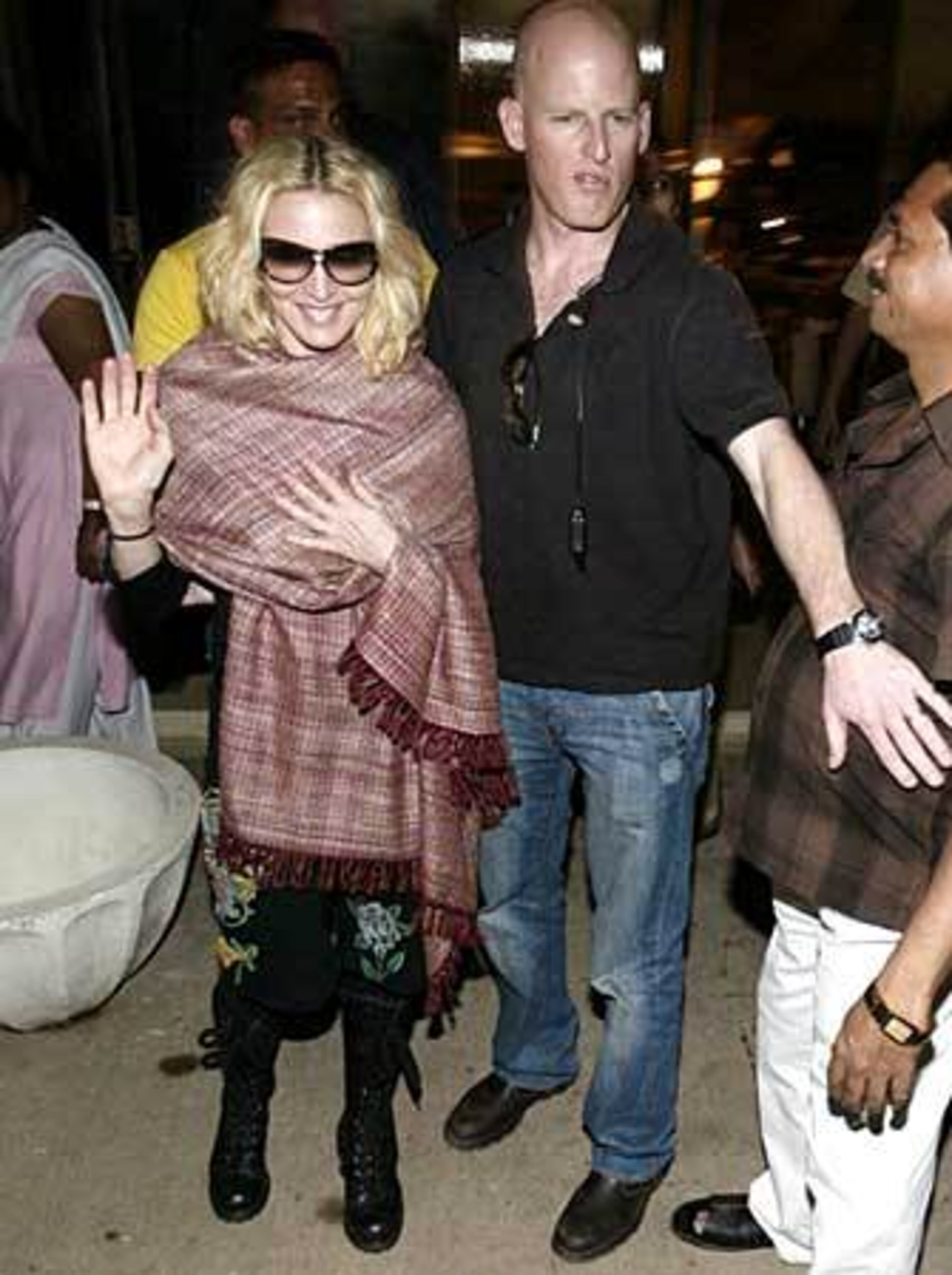Madonna, shielded by the bald guy, waves to photographers after visiting a store in Mumbai, India.