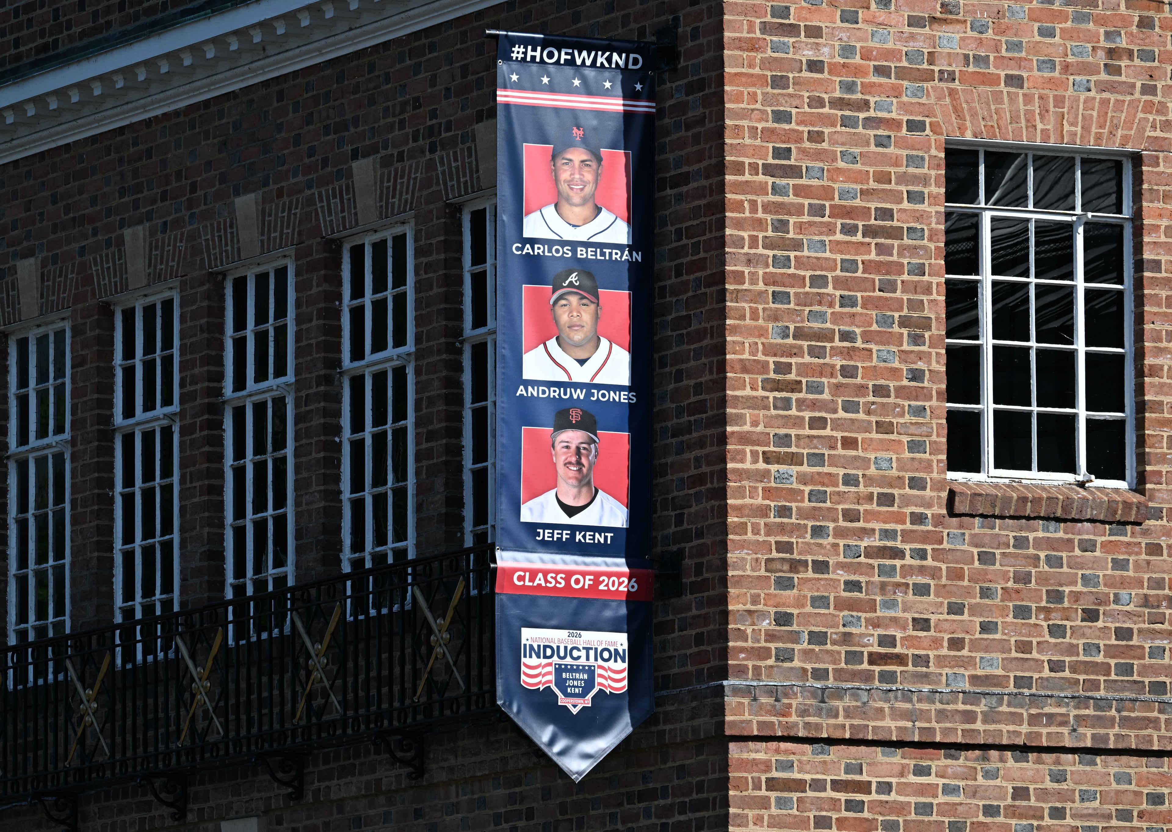 A banner featuring Class of 2026 inductees Andruw Jones, Carlos Beltrán and Jeff Kent is displayed outside the National Baseball Hall of Fame and Museum on Friday, July 24, 2026, in Cooperstown, N.Y. Andruw Jones is being inducted into the National Baseball Hall of Fame this Sunday as part of the Class of 2026, alongside Carlos Beltrán and Jeff Kent. He is recognized as one of the greatest center fielders in the league's history. Jones will become the 12th Braves player to be inducted into the Hall of Fame. (Hyosub Shin/AJC)