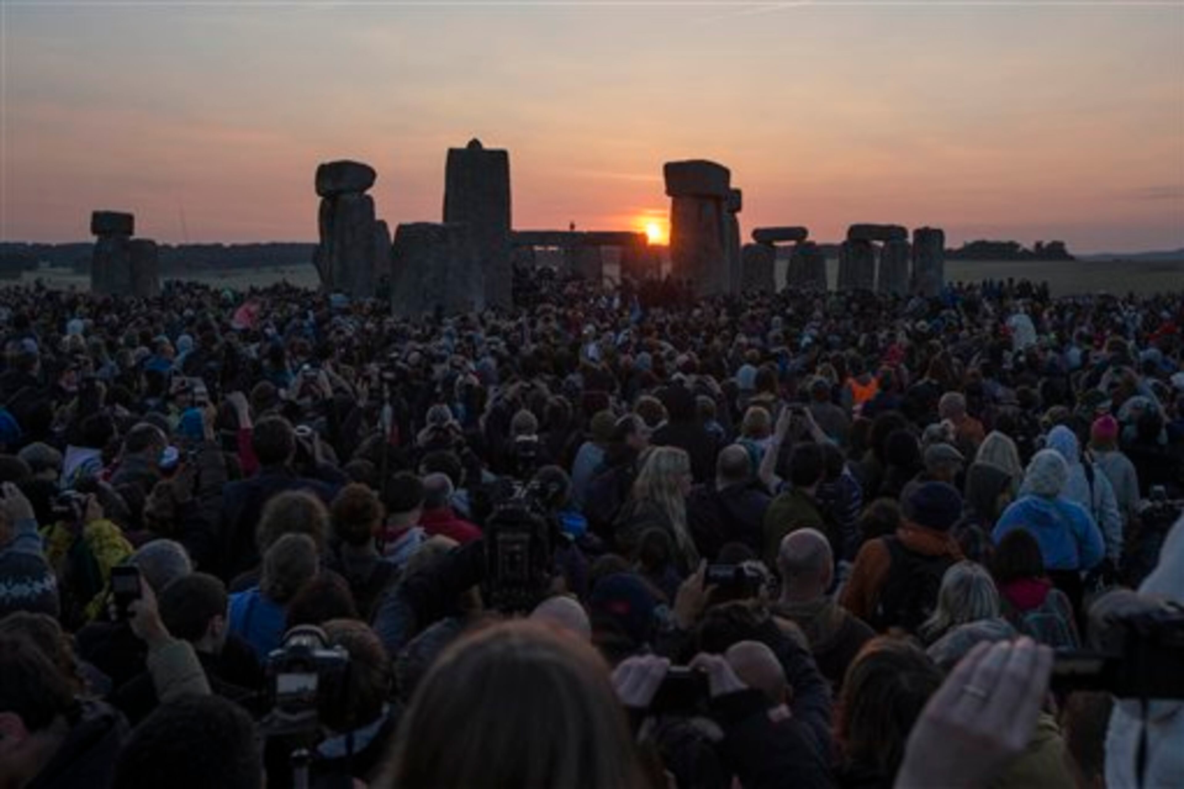 The sun rises as thousands of revelers gathered at the ancient stone circle Stonehenge, near Salisbury, England, to celebrate the summer solstice, the longest day of the year, Saturday, June 21, 2014. (AP Photo/Sang Tan)