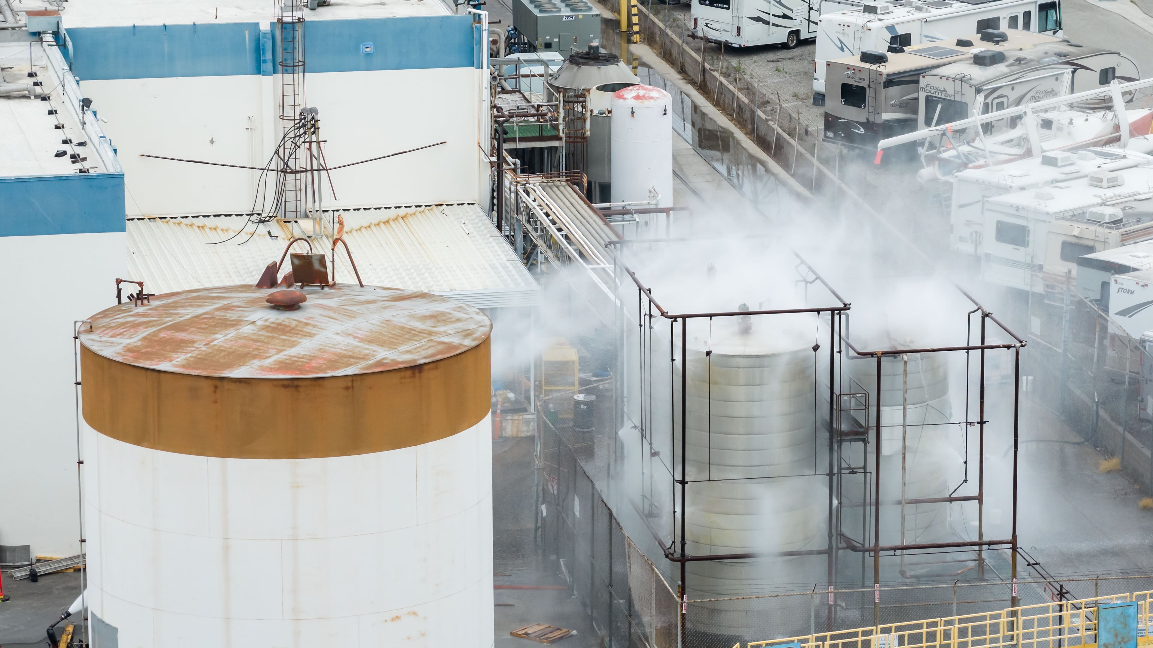 Water is sprayed on a damaged tank at GKN Aerospace in Garden Grove, Calif., on Sunday, May 24, 2026, after the tank containing a chemical used to make plastic parts overheated Thursday. (AP Photo/Ethan Swope)