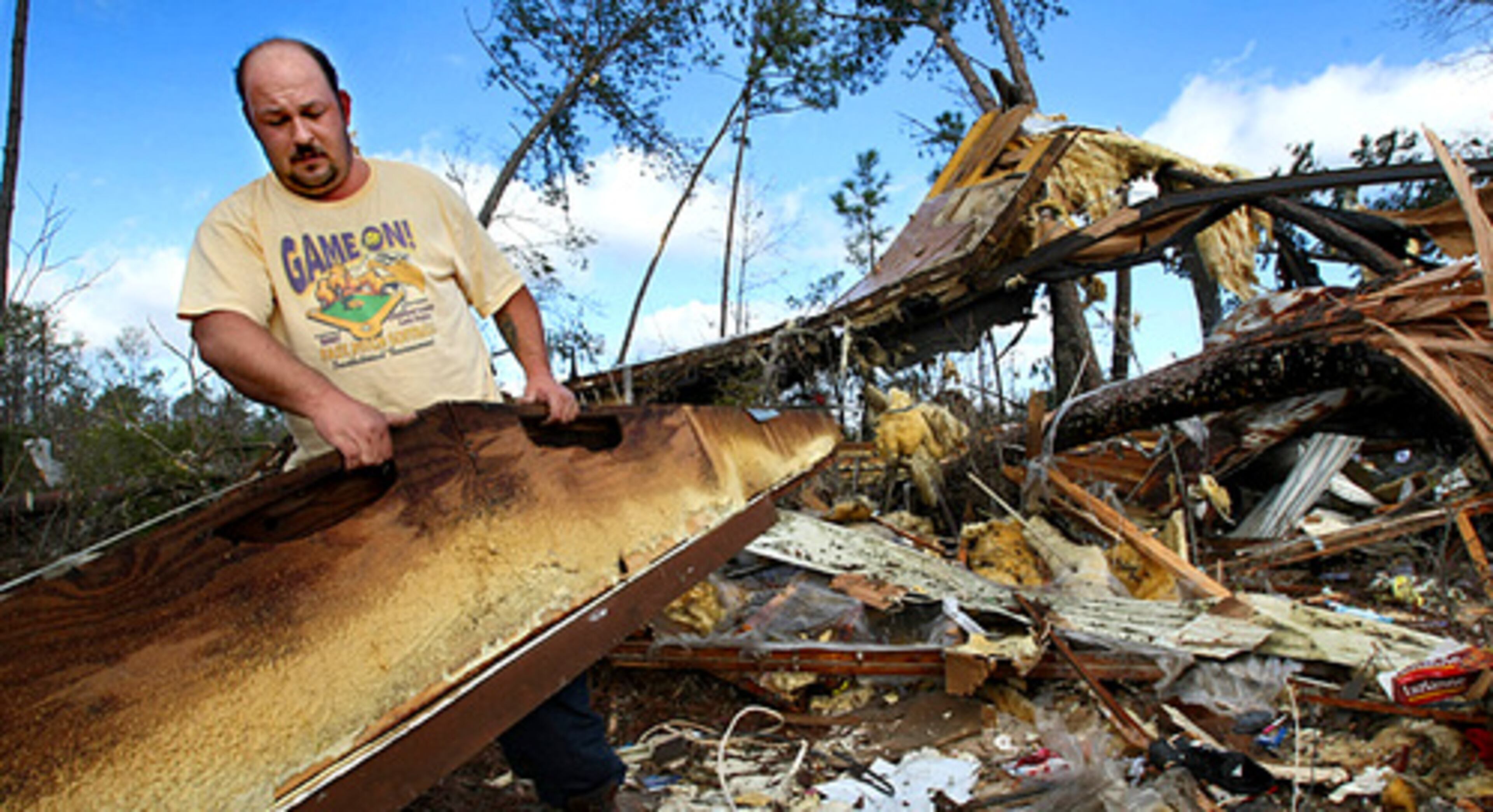 Johnny Moncrief pulls rubble away from his obliterated mobile home Monday morning after escaping with his wife and two children to their nearby parents' house three minutes before what appears to have been a tornado destroyed their home in Roberta in Crawford County, west of Macon.