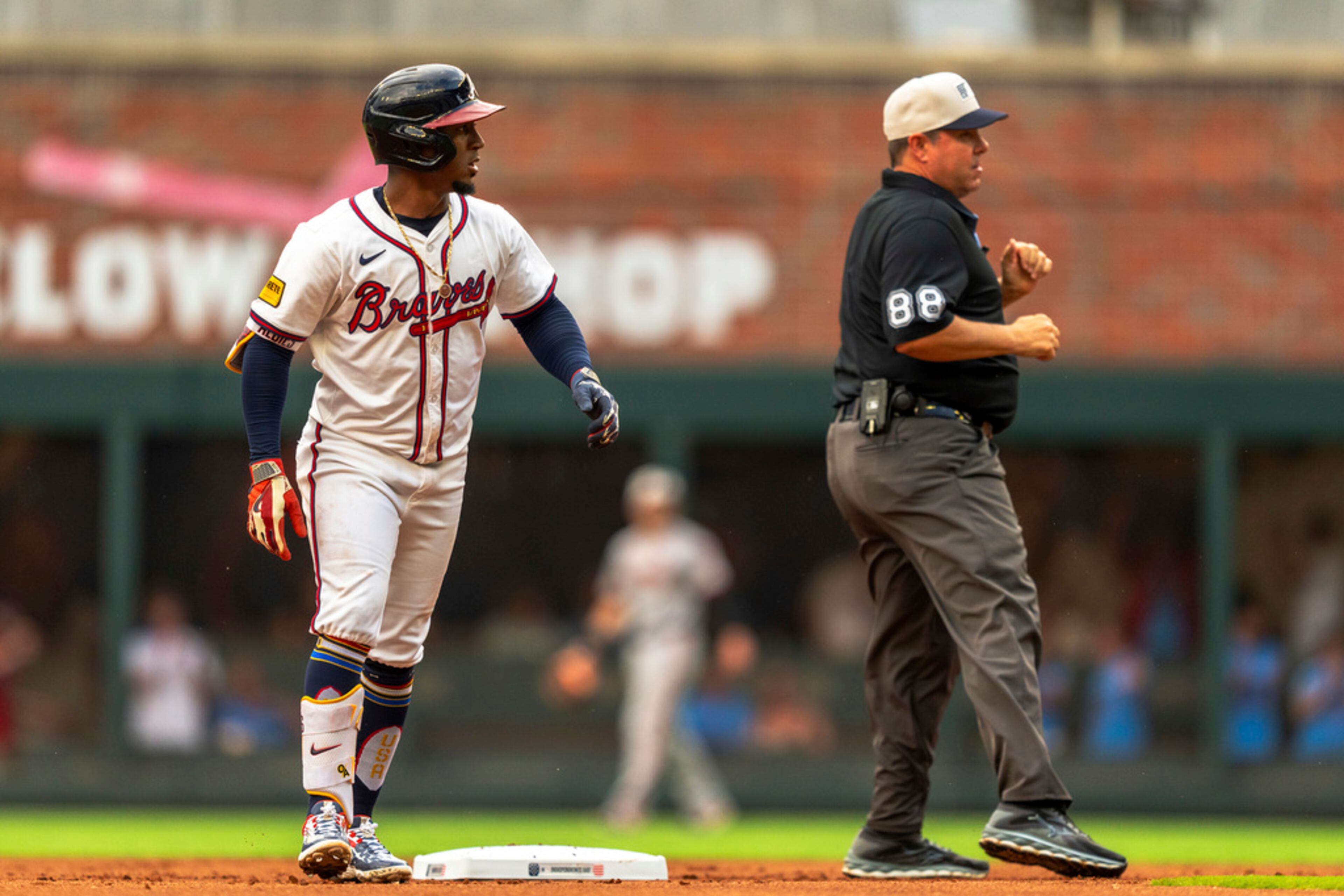 Atlanta Braves' Ozzie Albies, left, looks past an umpire, right, to Braves first base coach Tom Goodwin (not shown) in the first inning of a baseball game against the San Francisco Giants, Thursday, July 4, 2024, in Atlanta. (AP Photo/Jason Allen)