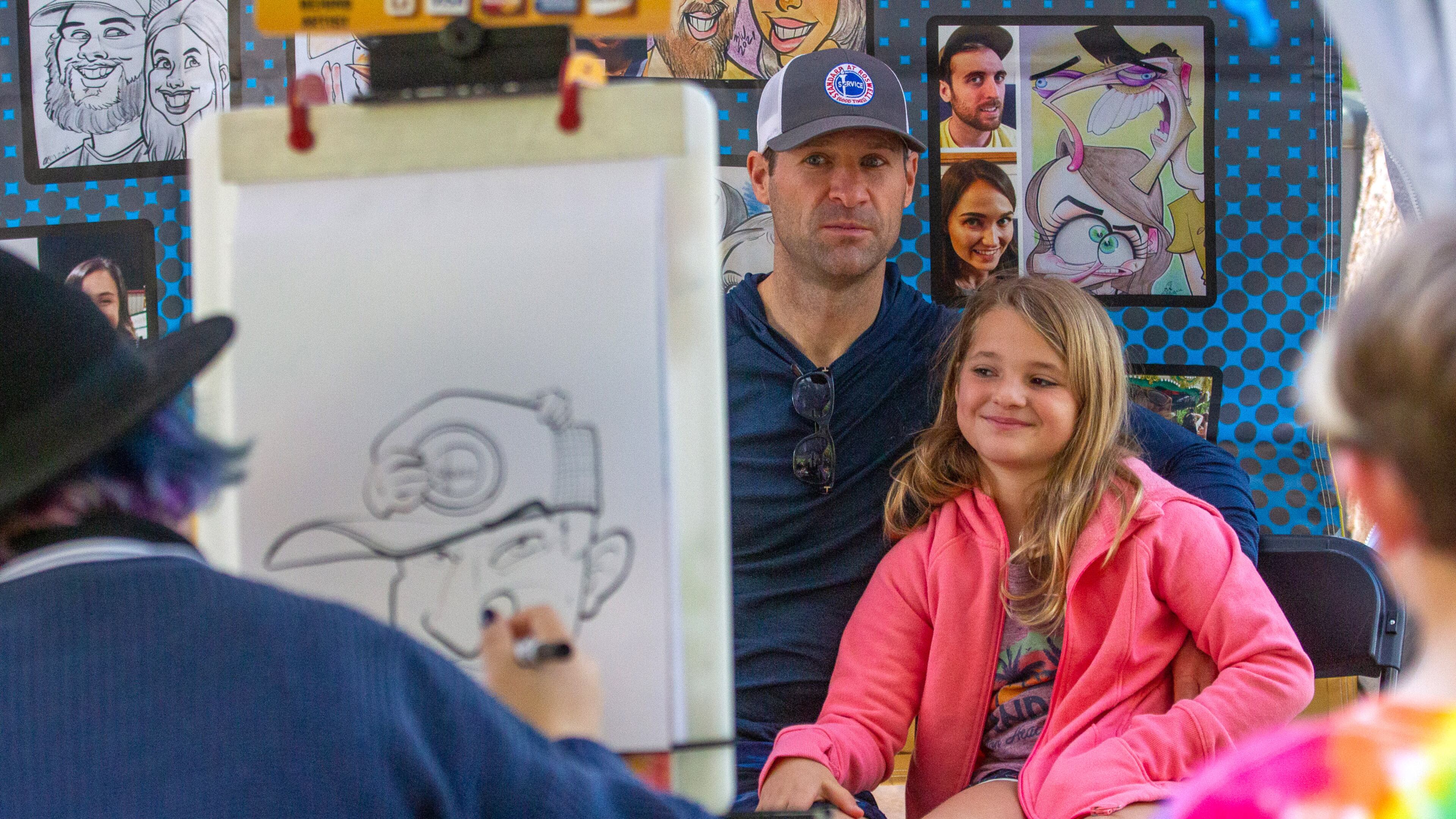 Mike Baumgartner and his daughter Lizzie sit for a caricature drawing during the Chastain Park Fall Arts Festival.