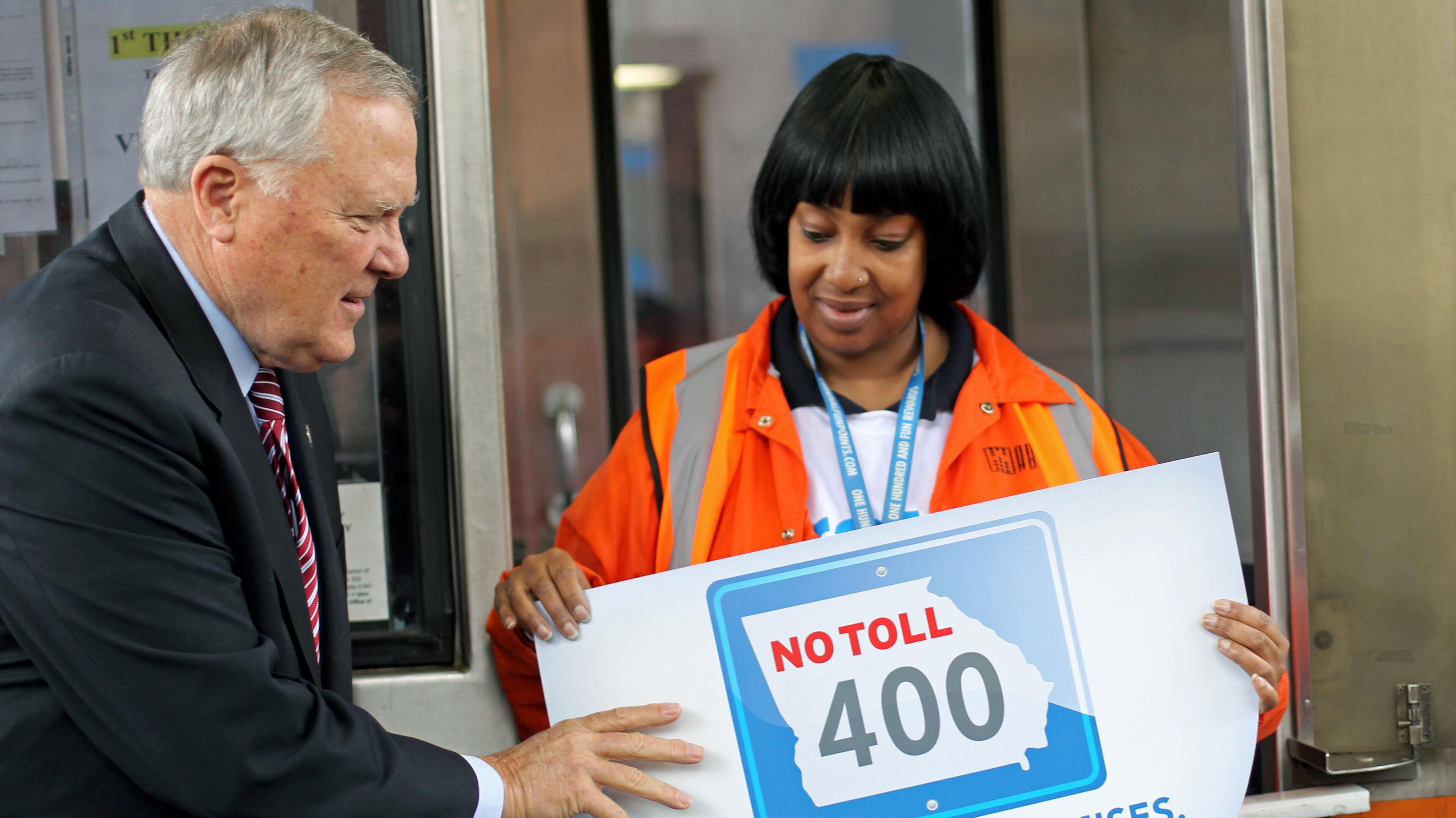 Gov. Nathan Deal and control room operator Yolanda Perry place a sign on the change basket to signify the closing of the GA 400 Toll Plaza Friday afternoon in Atlanta, Ga., November 22, 2013. The tool booth plaza opened on August 2, 1993. GA 400 was the state's first toll road. JASON GETZ / JGETZ@AJC.COM
