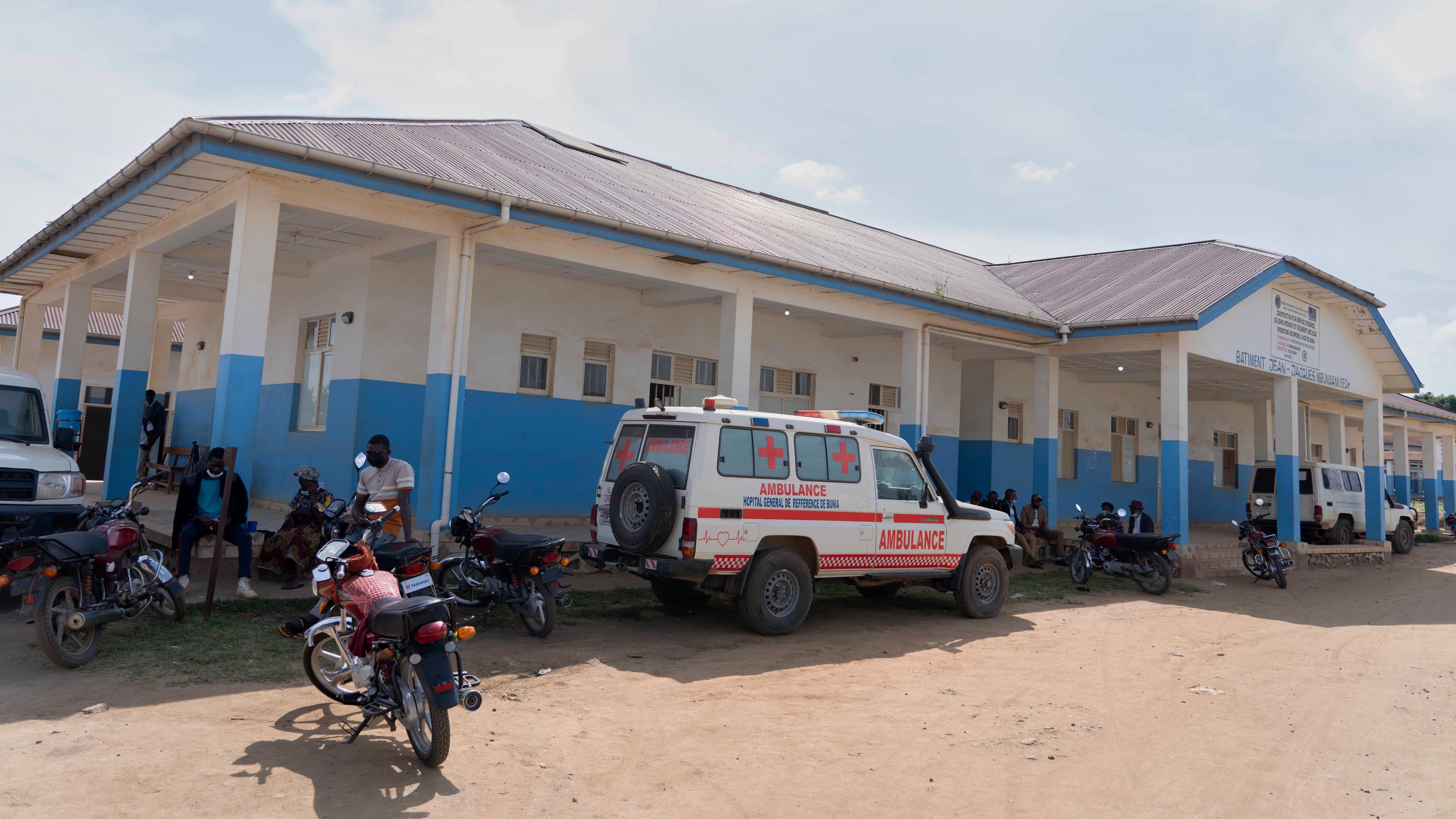 People wait near an ambulance at a hospital in Bunia, Congo, Sunday, May 17, 2026. (AP Photo/ Dirole Lotsima Dieudonne)