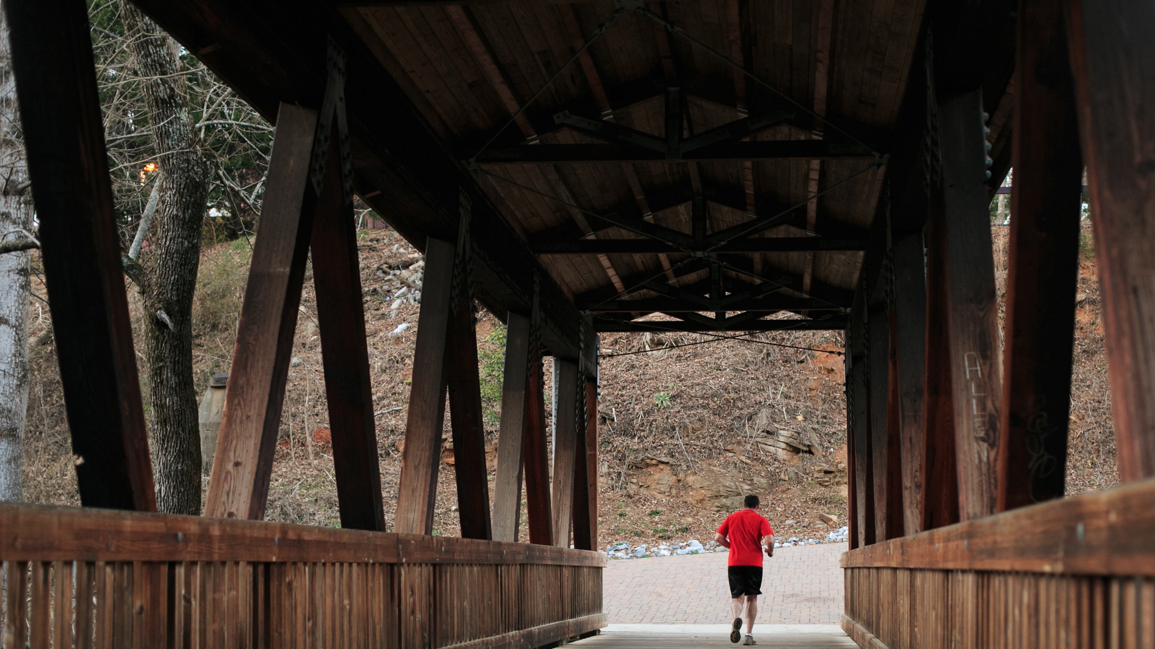 A runner travels across the Vickery Creek covered pedestrian bridge at Roswell's Old Mill Park in Roswell.