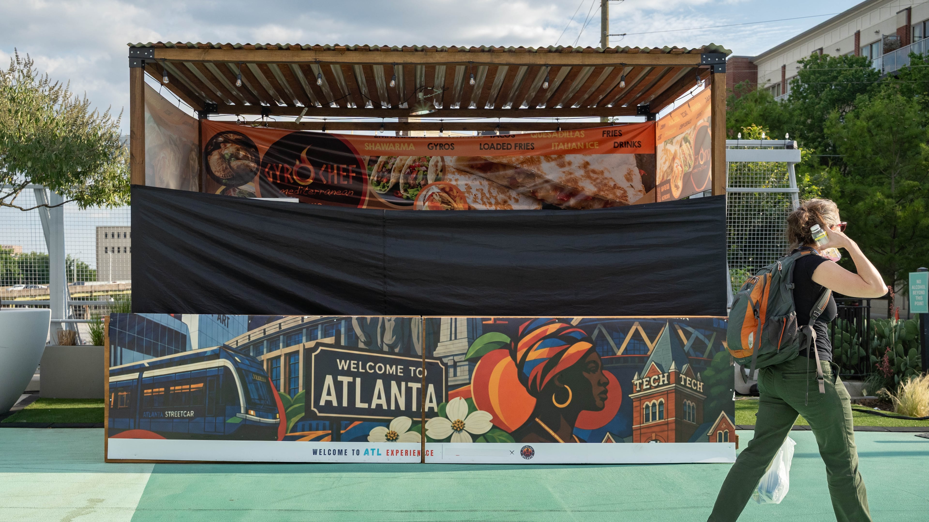 A shuttered Gyro Chef Mediterranean booth sits empty as a pedestrian passes by on the Steele Bridge in downtown Atlanta on June 24, 2026. (Ben Hendren for the AJC)