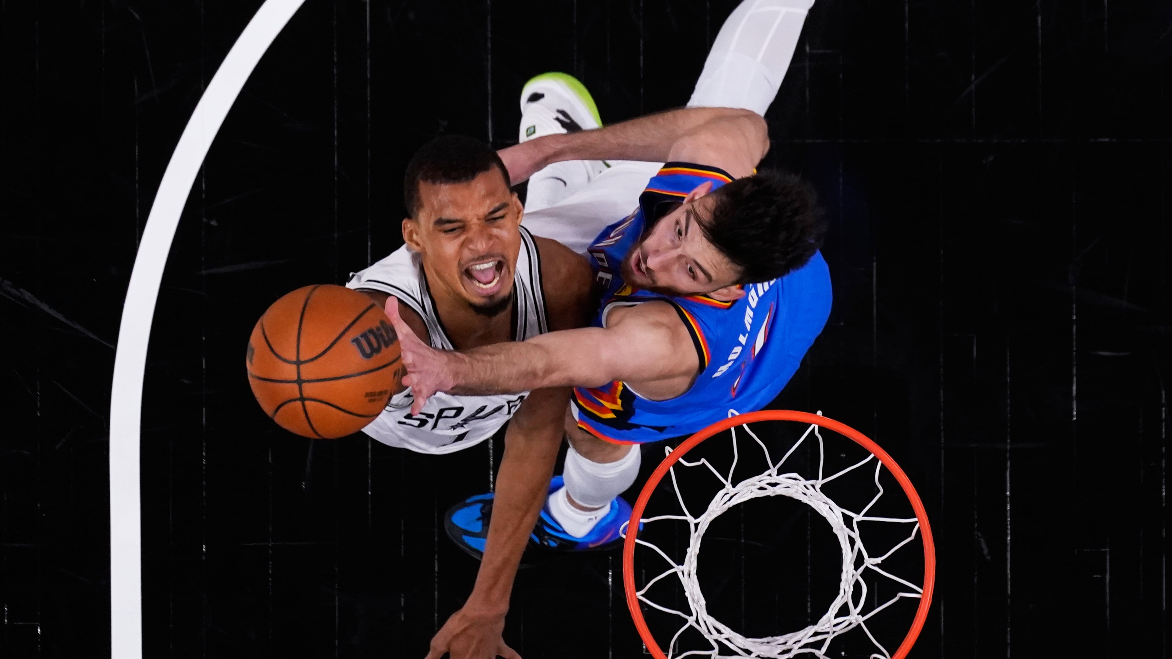 San Antonio Spurs forward Victor Wembanyama, left, scores against Oklahoma City Thunder center Chet Holmgren, right, during the first half in Game 4 in the Western Conference finals NBA basketball playoffs series in San Antonio, Sunday, May 24, 2026. (AP Photo/Eric Gay)