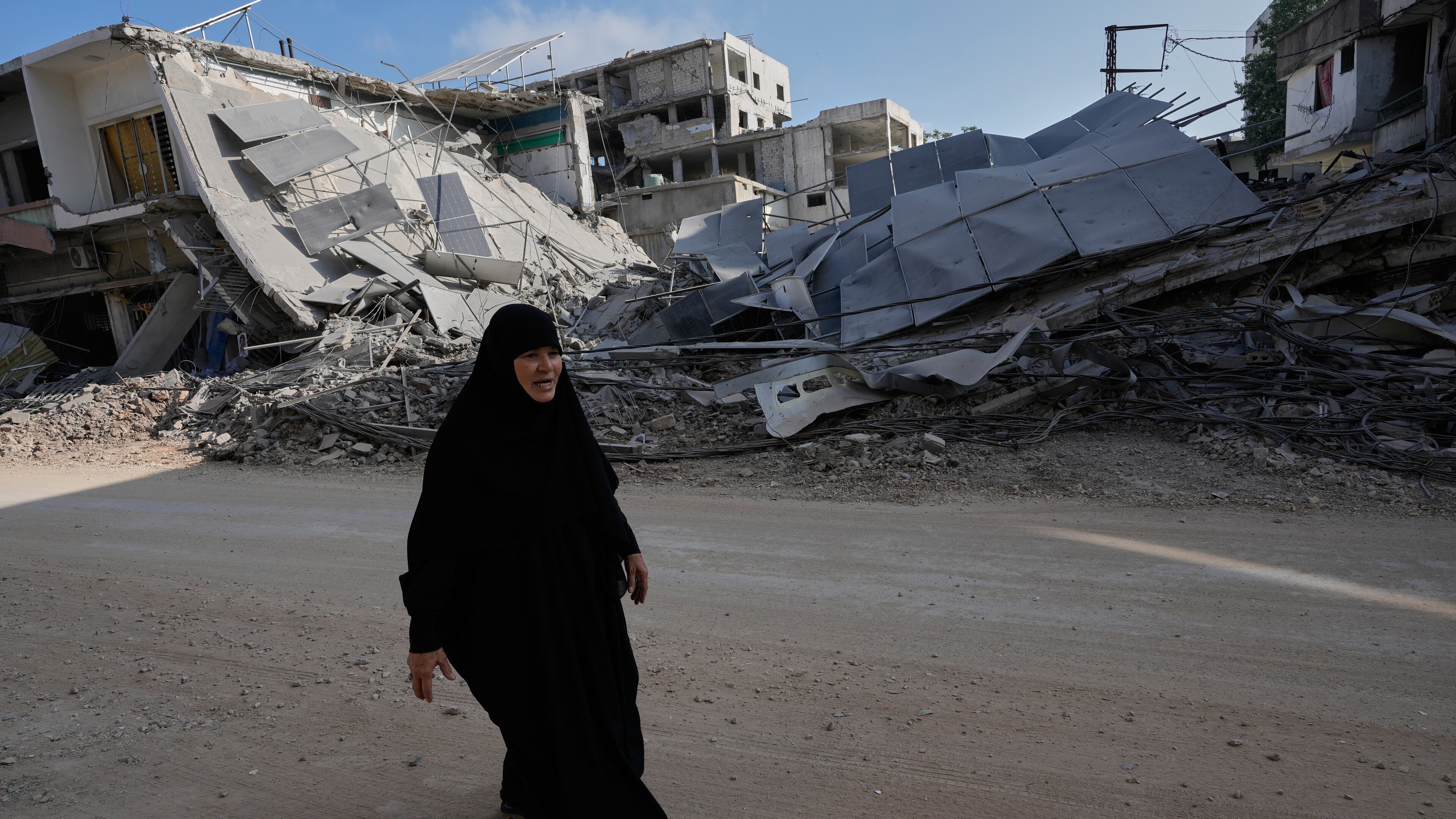 A woman returns to her village following the announcement of an initial ceasefire agreement between the United States and Iran, walks at her destroyed neighbourhood in Nabatiyeh town, southern Lebanon, Tuesday, June 16, 2026. (AP Photo/Hussein Malla)