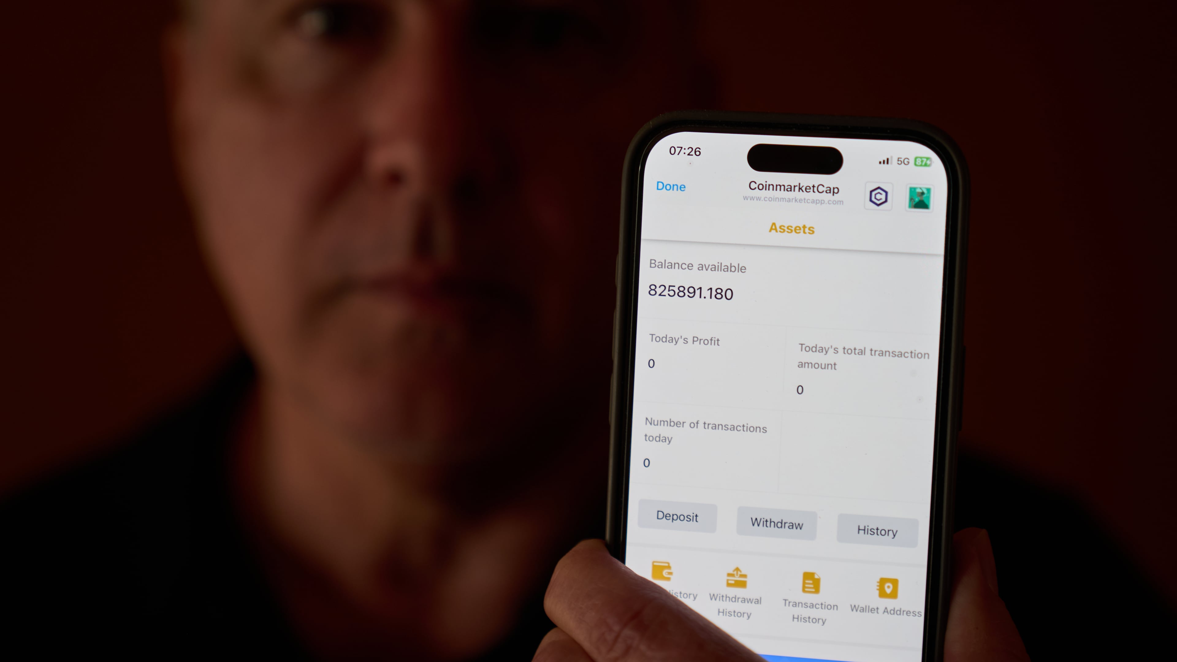 Chris Colocousis holds up a screenshot of the fake app where he invested his savings showing his account had more than doubled to nearly $826,000 as part of a scam in which he says he lost $400,000 at his home in Raynham, Mass., Tuesday, March 10, 2026. (AP Photo/David Goldman)