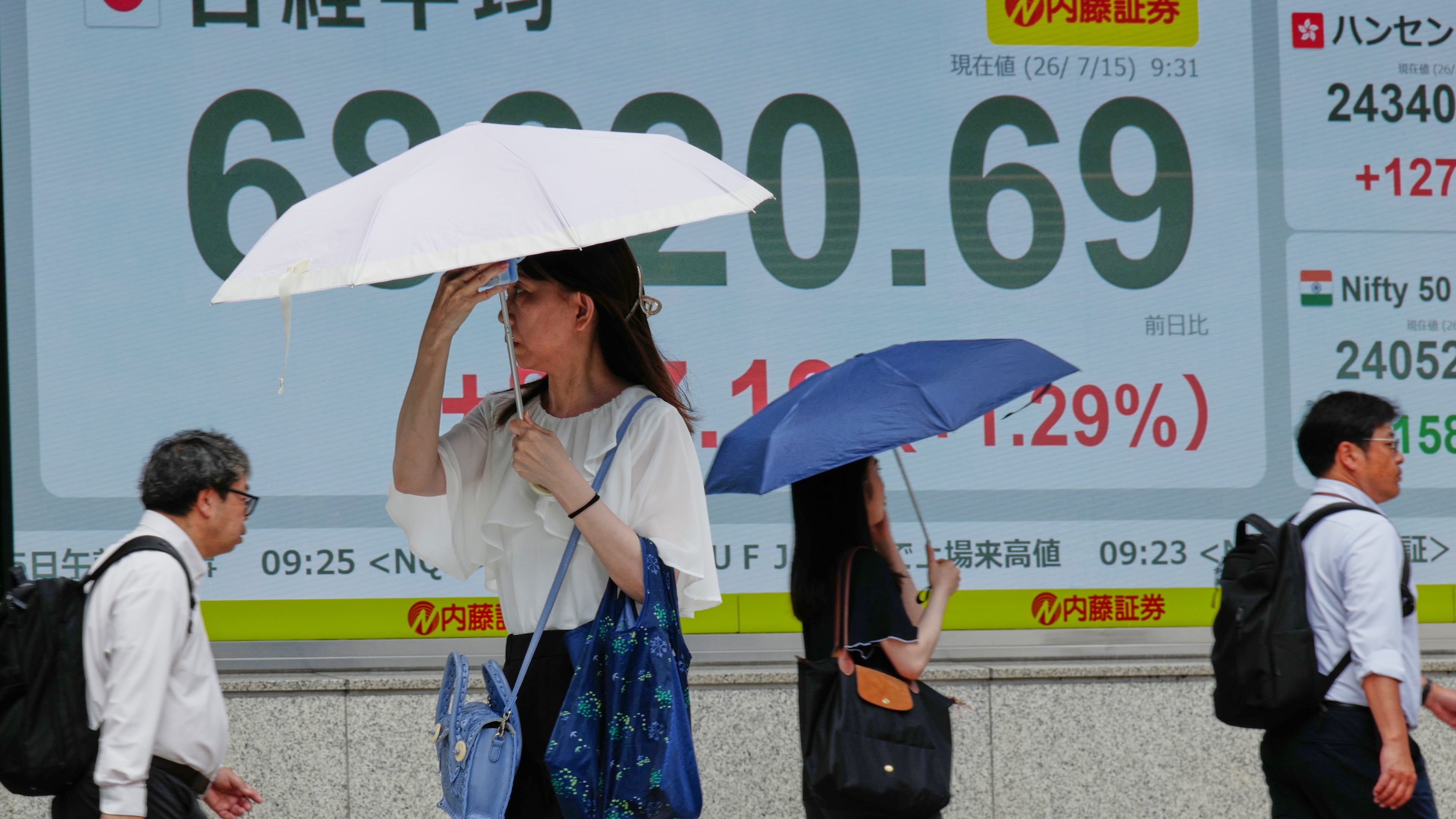 People walk in front of an electronic stock board showing Japan's Nikkei 225 index at a securities firm Wednesday, July 15, 2026, in Tokyo. (AP Photo/Eugene Hoshiko)