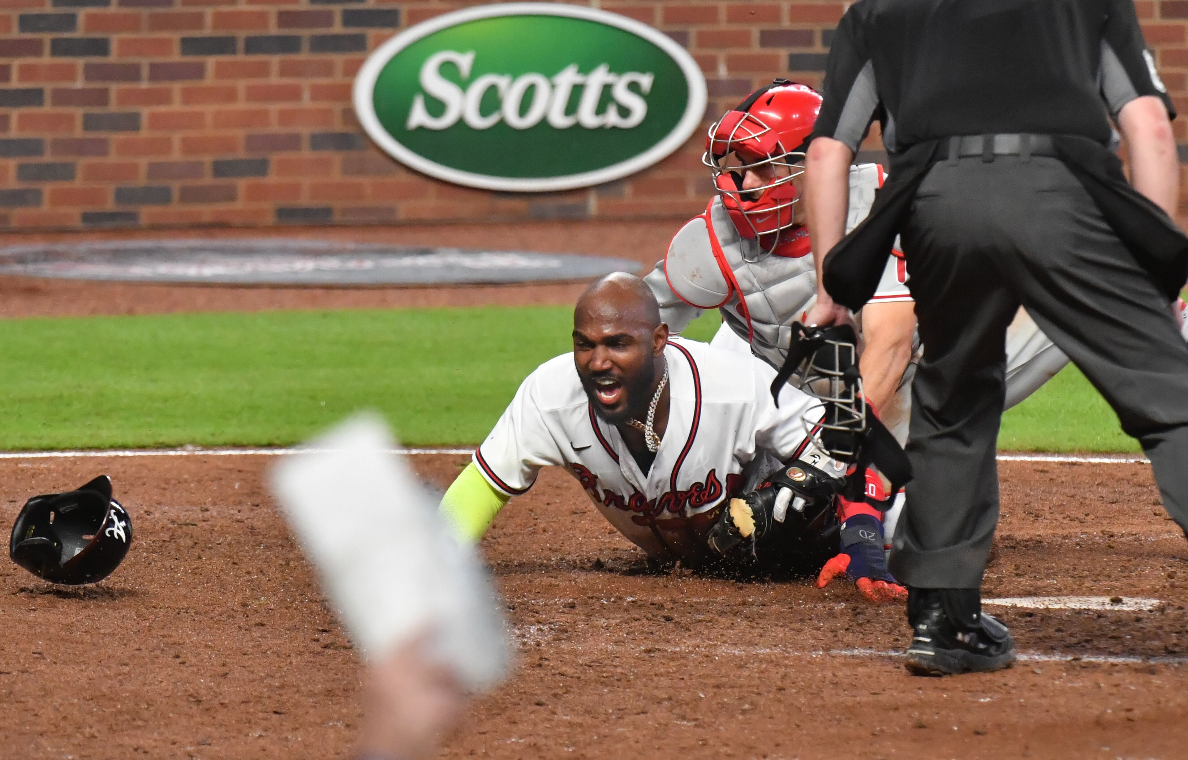 Braves left fielder Marcell Ozuna (20) scores past Philadelphia Phillies catcher J.T. Realmuto (10) during the 8th inning. (Hyosub Shin / Hyosub.Shin@ajc.com)