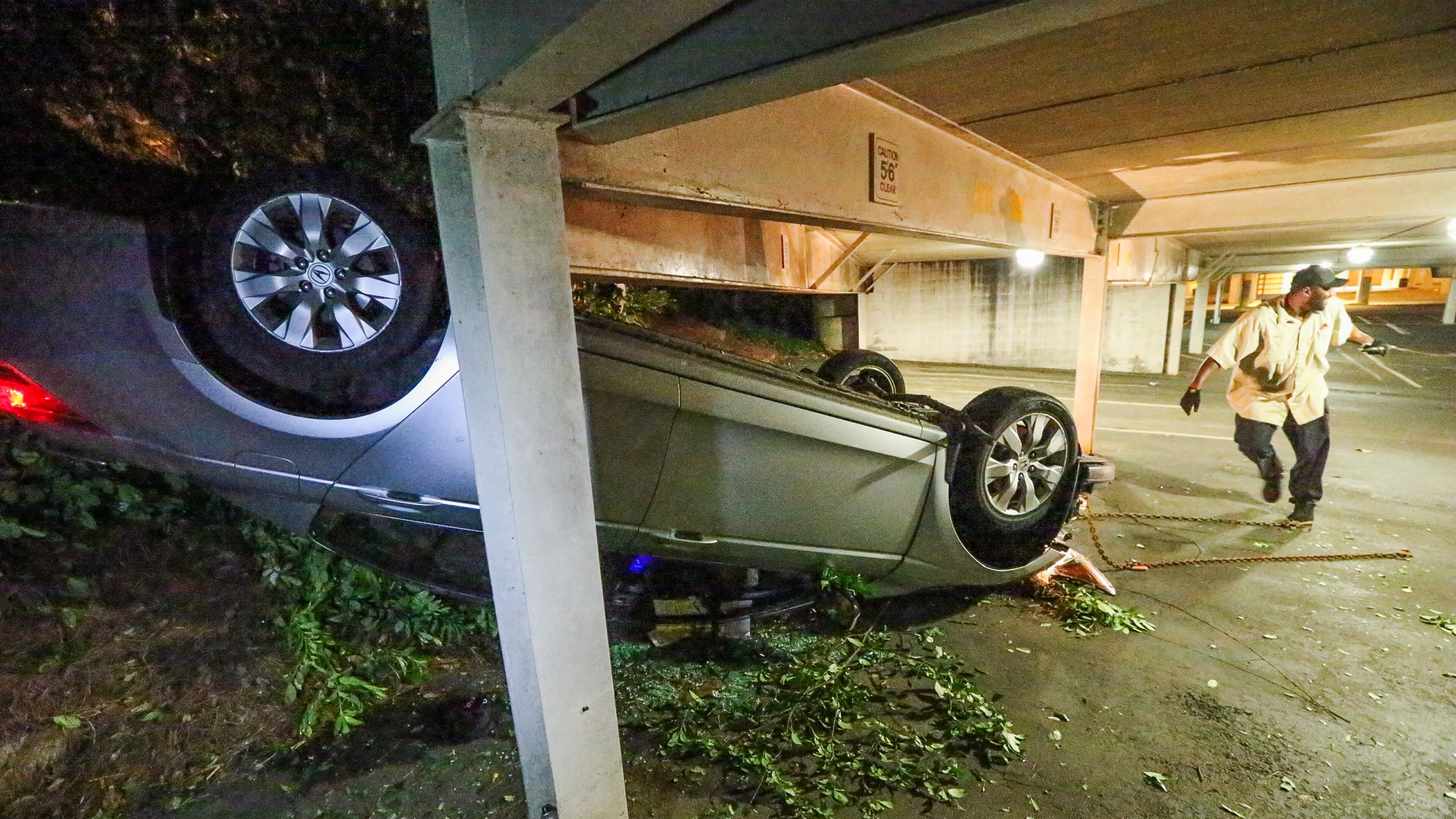 A tow truck operator works to remove a wrecked car from a Buckhead parking garage. JOHN SPINK / JSPINK@AJC.COM