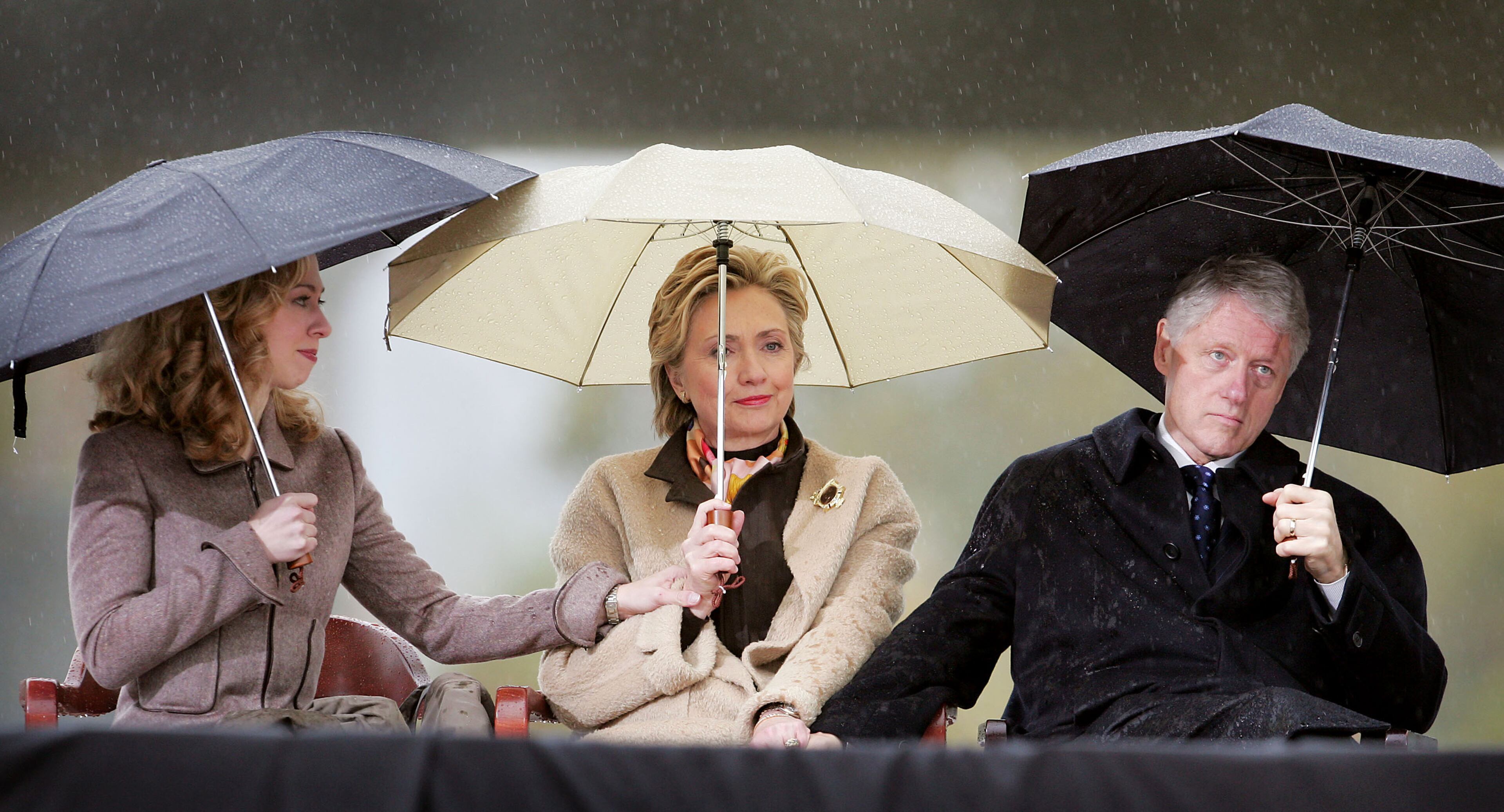 Former U.S. President William J. Clinton (R), his wife U.S. Senator Hillary Rodham Clinton (D-NY) and daughter Chelsea (L) listen to speakers at the dedication of the William J. Clinton Presidential Center November 18, 2004 in Little Rock, Arkansas. An estimated 30,000 spectators gathered in the rain on the grounds of the library to view the dedication of the $165 million facility. (Photo by Scott Olson/Getty Images)