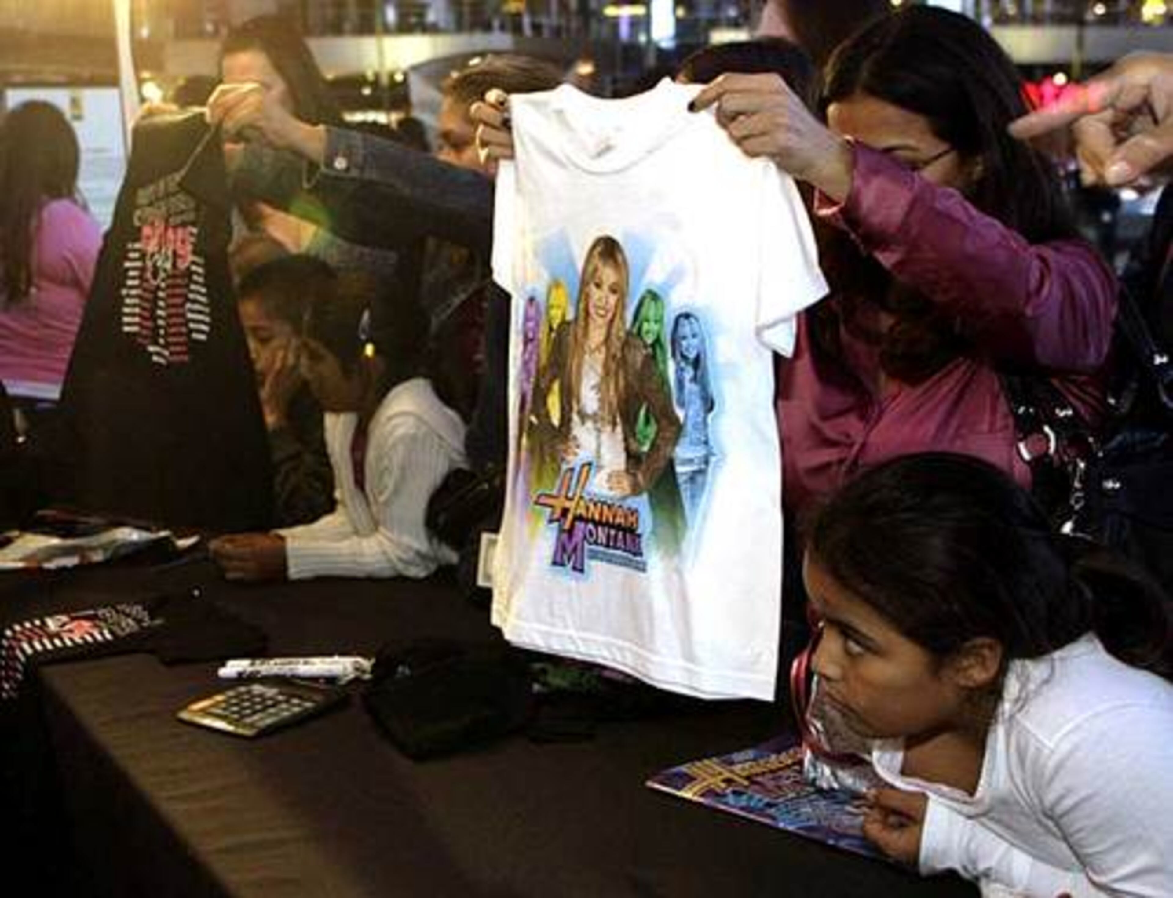 Fans of Miley Cyrus, star of The Disney Channel's series "Hannah Montana," buy souvenir T-shirts at the Ultimate Miley Party Bus Tour 2007.