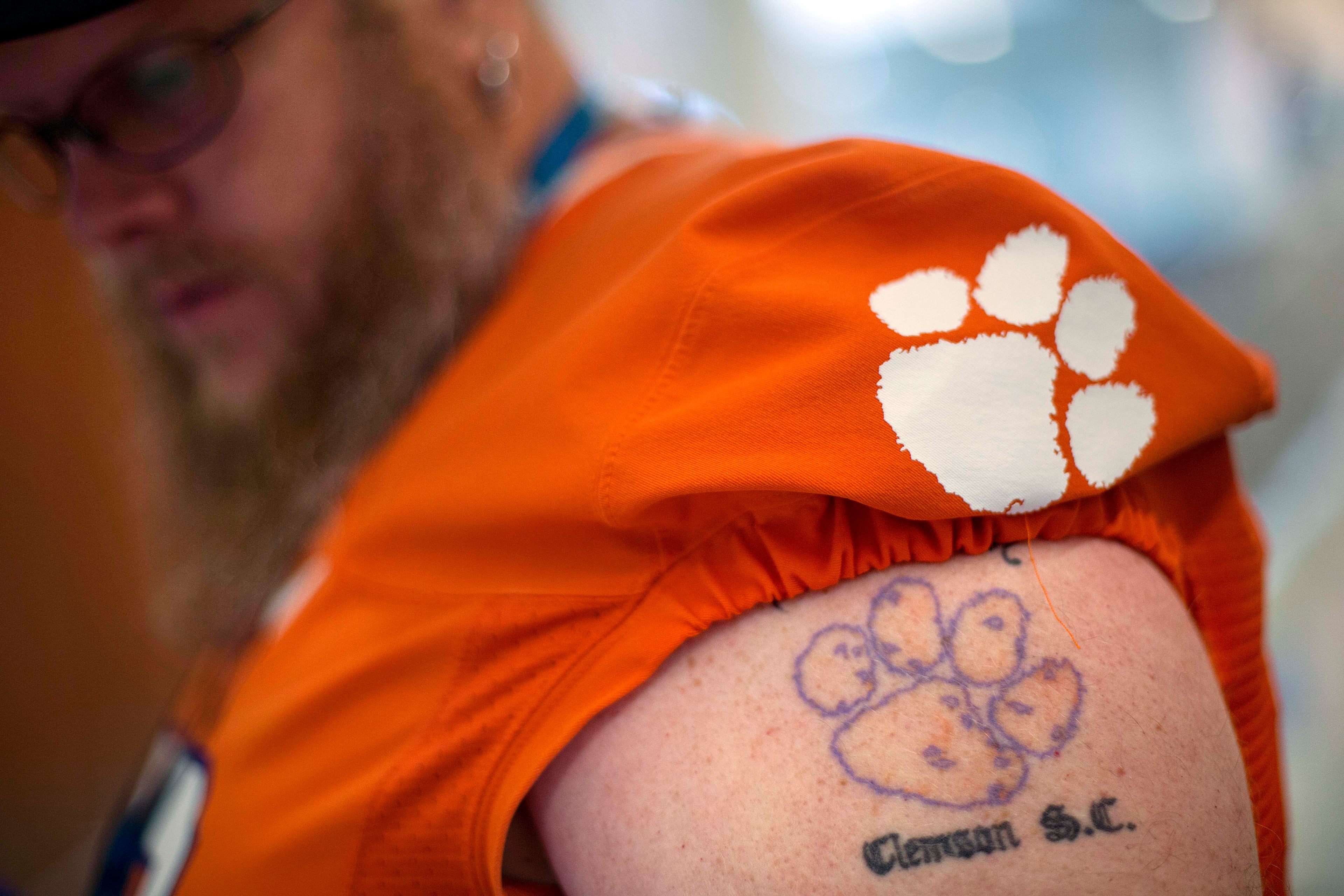 Steven Lyda, of Greer S.C., tours the College Football Hall of Fame with a tattoo of the Clemson Tiger's paw decorating his arm, Wednesday, Aug. 13, 2014, in Atlanta. "College football is almost a religion in the South," said Lyda. "Ain't nothing like it." (AP Photo/David Goldman)