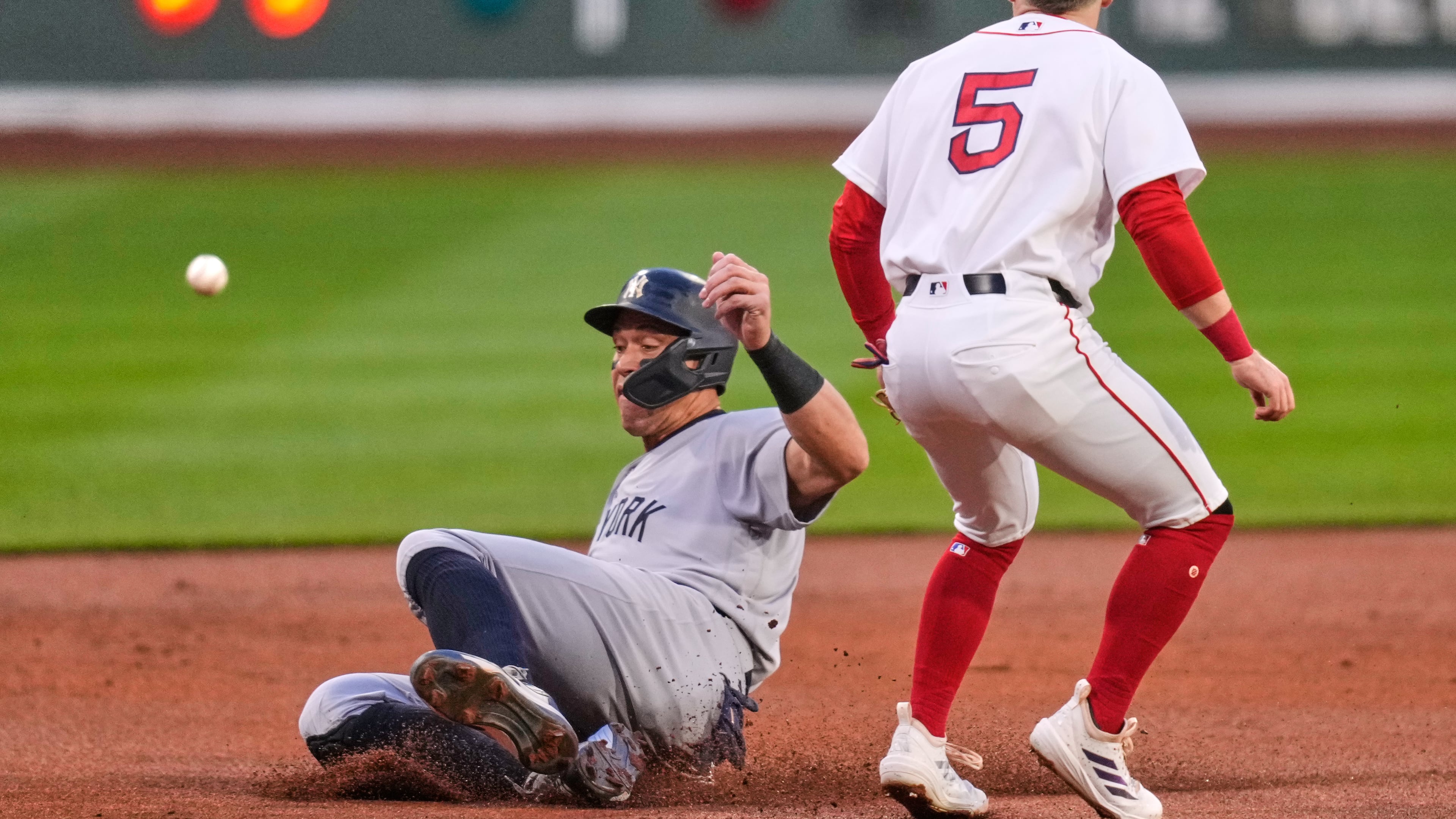 New York Yankees' Aaron Judge, left, beats the throw to Boston Red Sox third baseman Caleb Durbin (5) while advancing on a double by Giancarlo Stanton during the first inning during of a baseball game at Fenway Park, Wednesday, April 22, 2026, in Boston. (AP Photo/Charles Krupa)