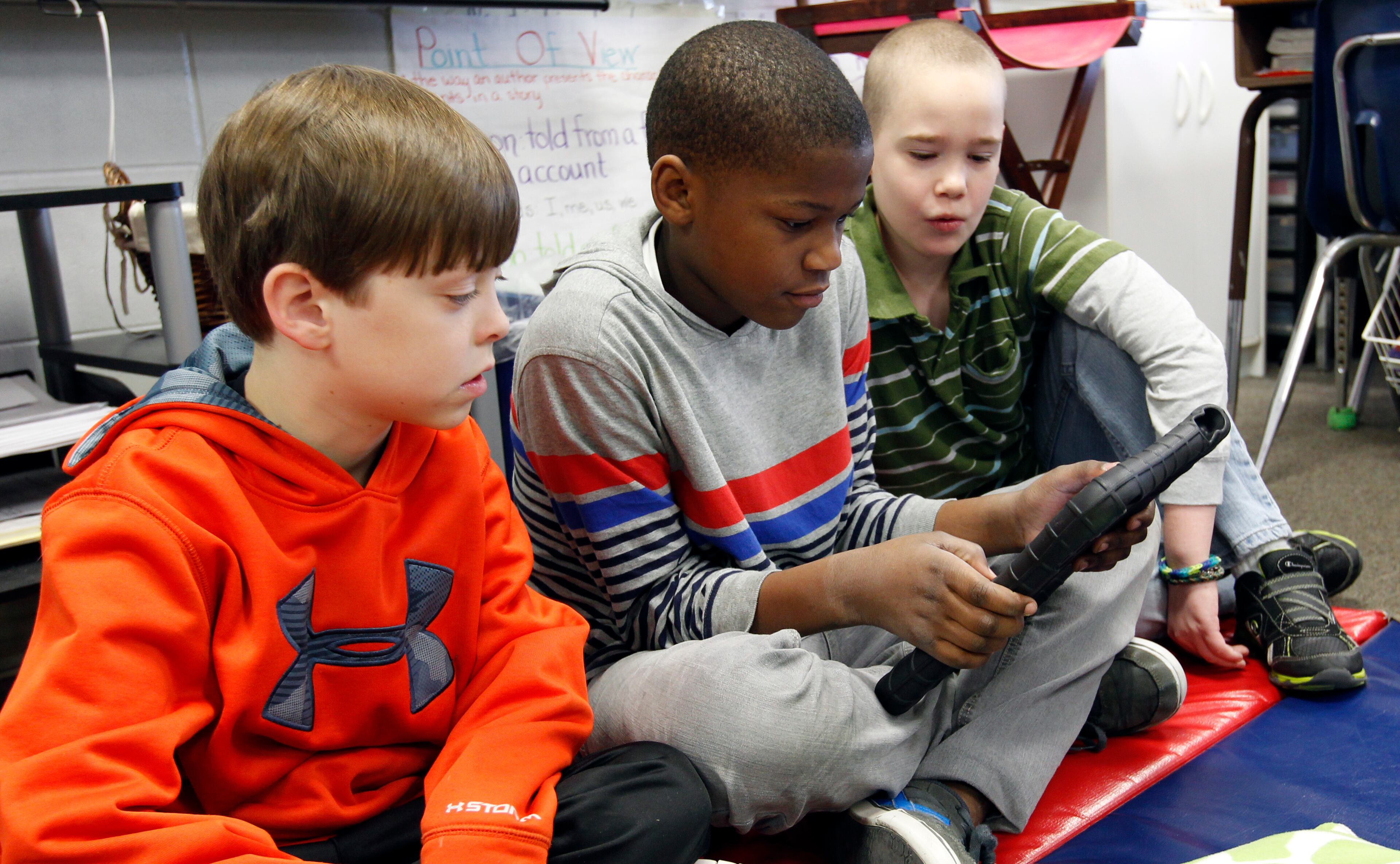 Students from Oak Mountain Intermediate school, from left, Zachary Henson, Camren Lyaka, and Eli Fieldsplay on an iPad on Wednesday, Jan. 29, 2014, in Indian Springs, Ala. About 80 children and 20 adults spent the night at the school due to a winter storm. Overnight, the South saw fatal crashes and hundreds of fender-benders. Jackknifed 18-wheelers littered Interstate 65 in central Alabama. (AP Photo/Butch Dill)