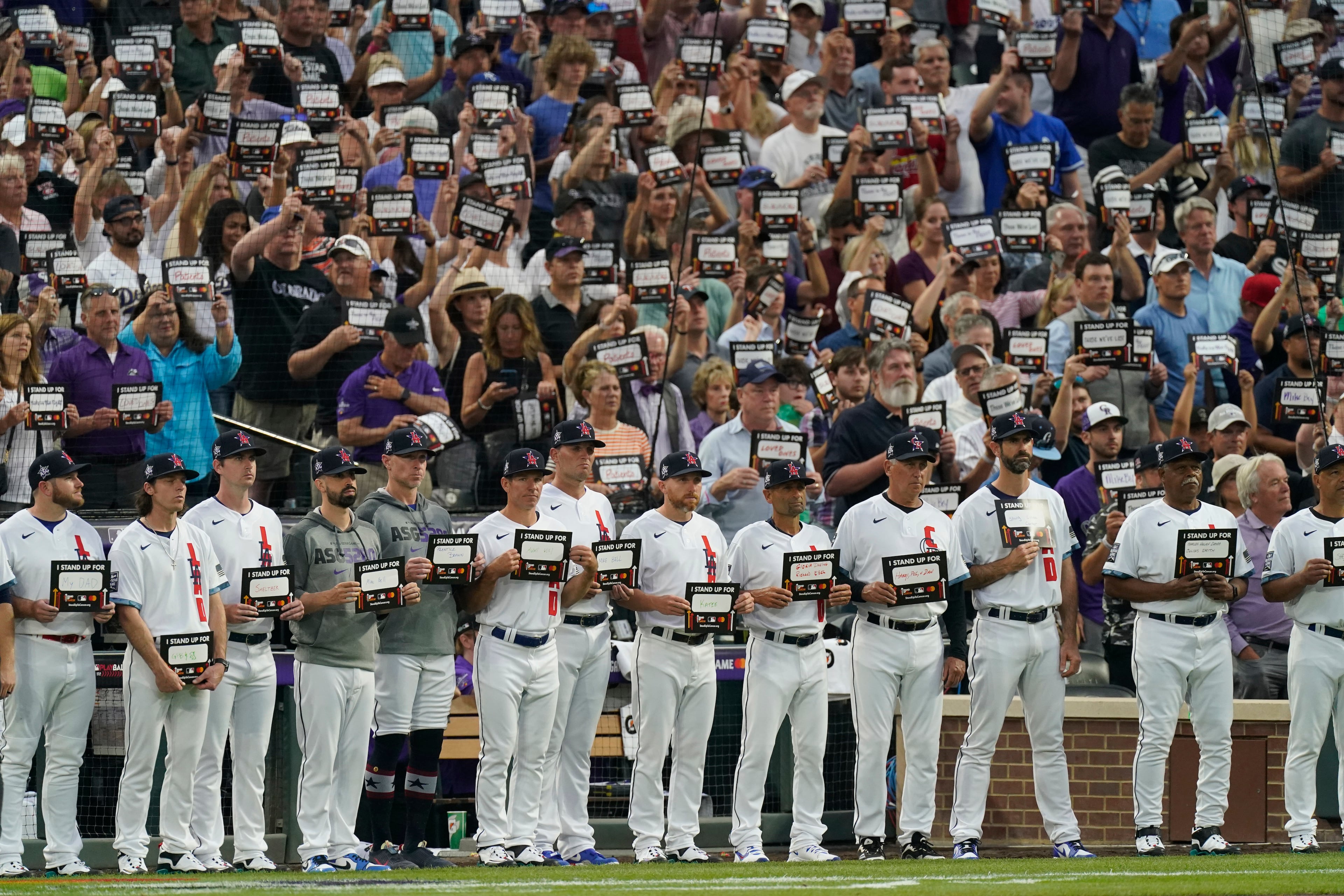 National League players hold signs for cancer awareness during the fifth inning of the MLB All-Star baseball game, Tuesday, July 13, 2021, in Denver. (AP Photo/Gabriel Christus)
