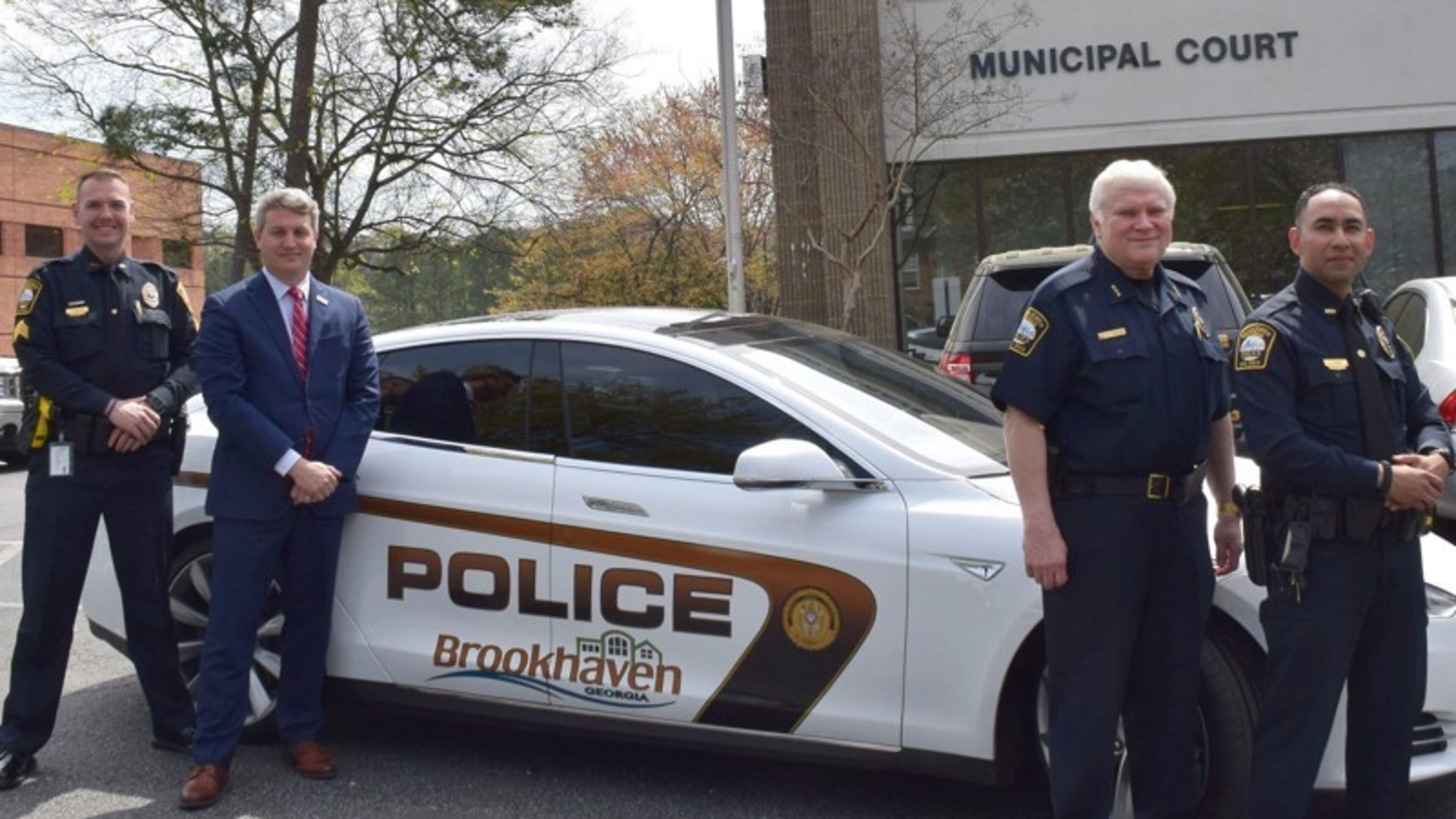 Sgt. Jake Kissel (left), Mayor John Ernst, Police Chief Gary Yandura and Officer Carlos Nino with Brookhaven's 2015 Tesla Model S, which will undergo performance tests at the Georgia Public Safety Training Center on Tuesday.