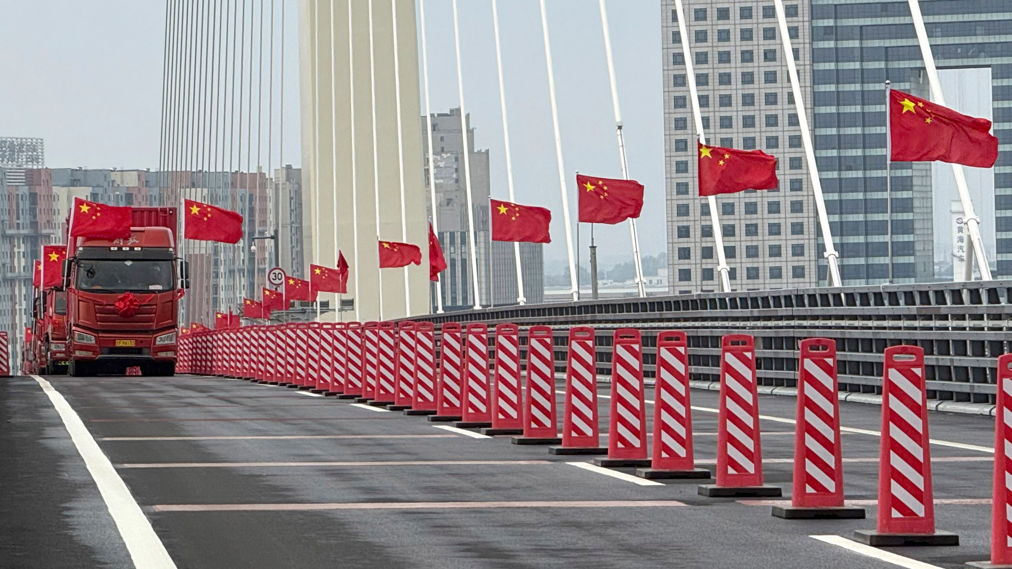 In this photo released by Xinhua News Agency, trucks flying Chinese flags are seen during the opening ceremony of the new China-North Korea Yalu River Bridge at the border between the two countries on Thursday, Oct. 15, 2026. (Pan Yulong/Xinhua via AP)