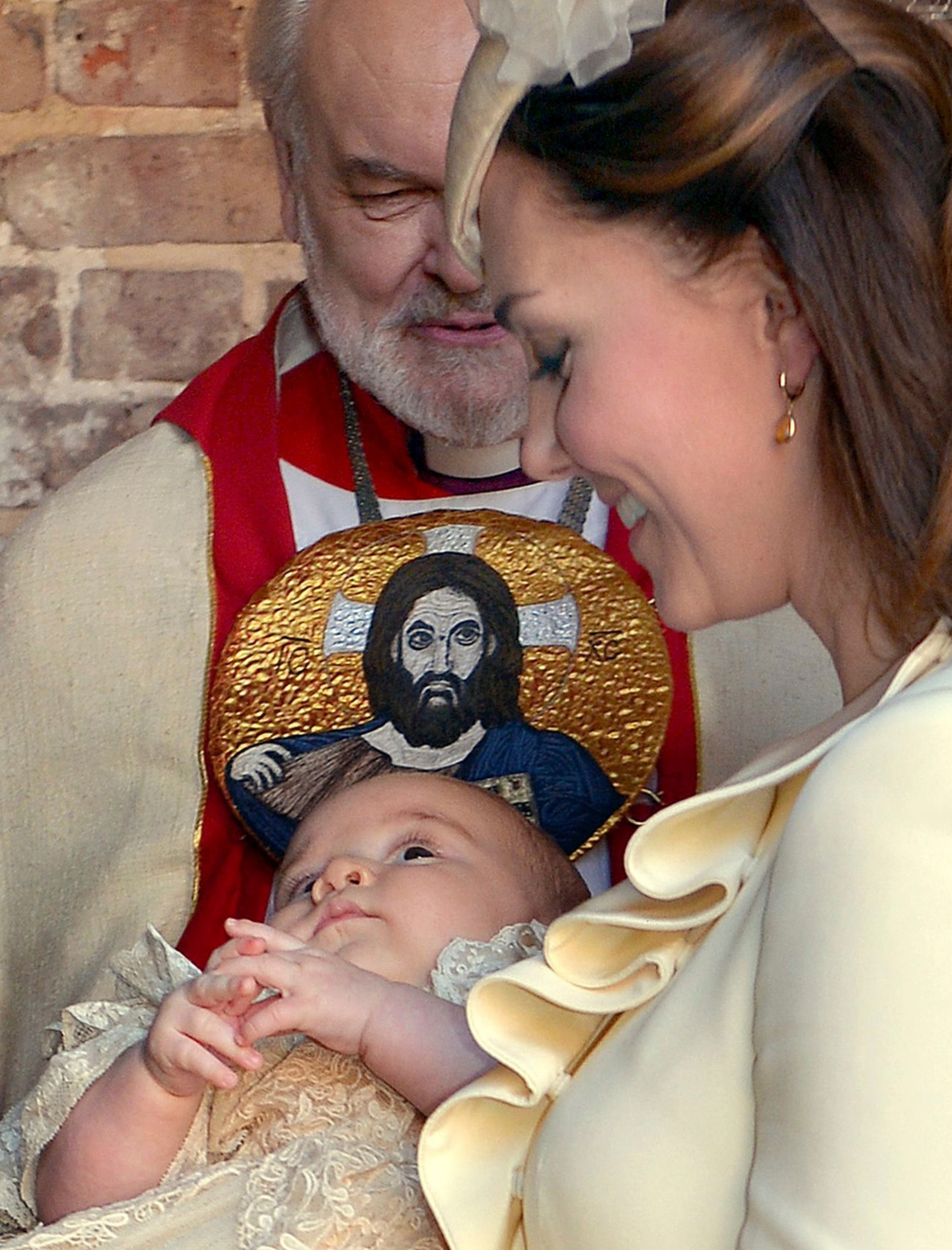 Kate Duchess of Cambridge carries her son Prince George after his christening at the Chapel Royal in St James's Palace in London, with the Bishop of London Richard Chartres behind, Wednesday Oct. 23, 2013. The prince was christened Wednesday with water from the River Jordan at a rare four-generation gathering of the royal family in London. (AP Photo/John Stillwell, Pool)
