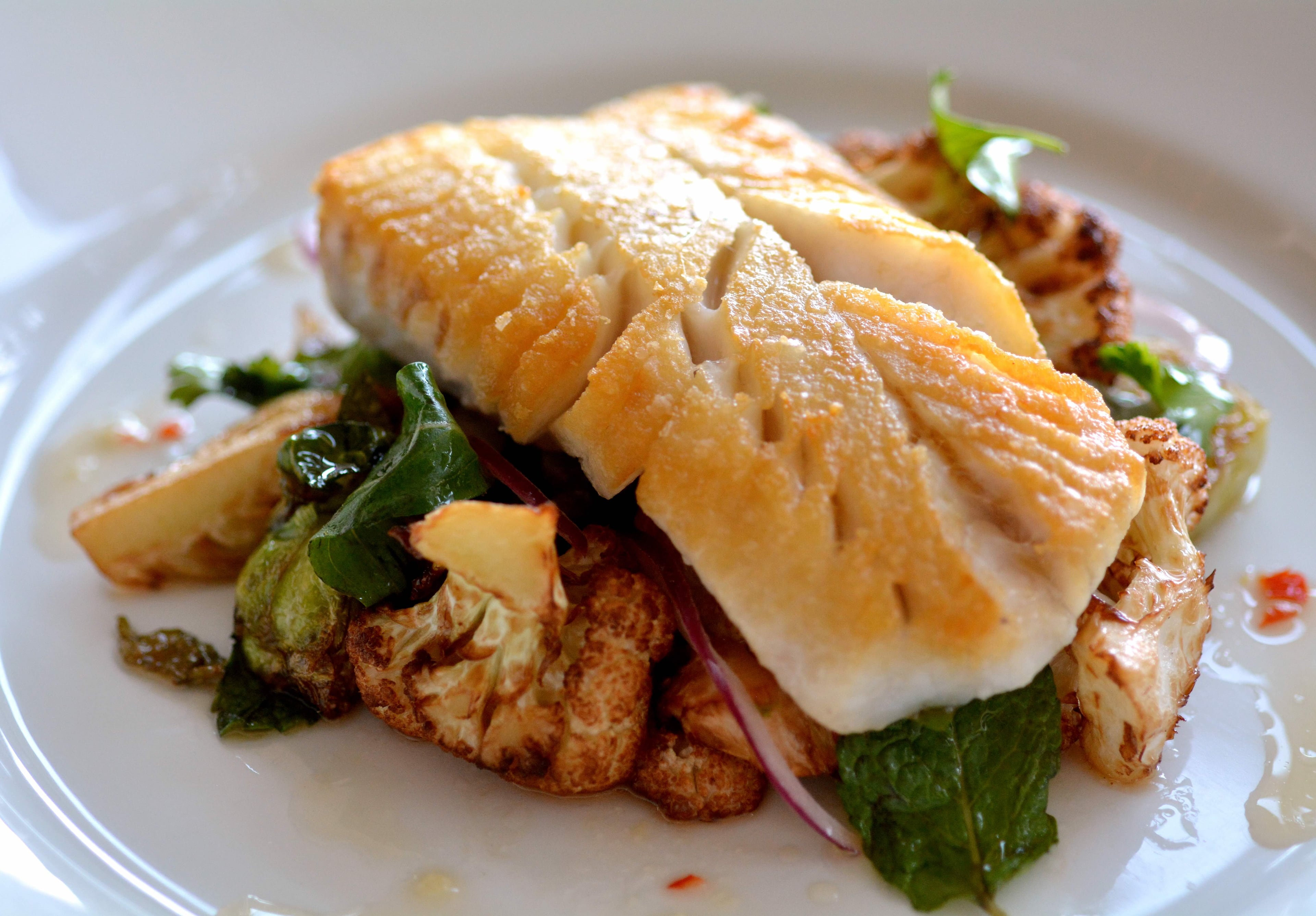 The pan-roasted blue cod at Seed Kitchen & Bar is paired with caramelized Brussels sprouts, cauliflower, Thai herb vinaigrette and red onion. (Courtesy of Seed Kitchen & Bar)