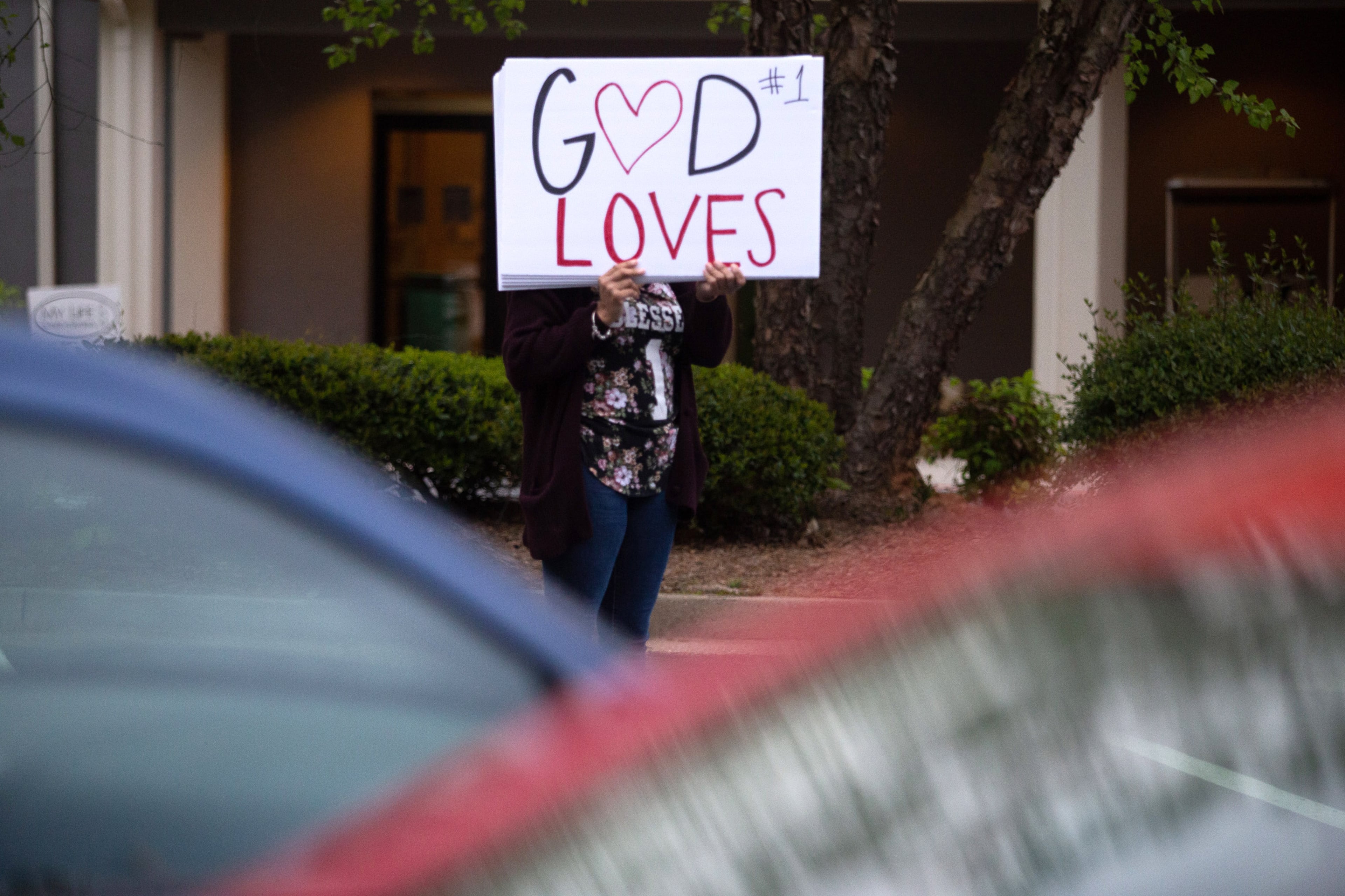 Robbie Dunbar holds up a sign during the sunrise Easter Drive-in church service at the Life Church Smyrna Assembly of God Sunday in Smyrna April 12, 2020. STEVE SCHAEFER / SPECIAL TO THE AJC